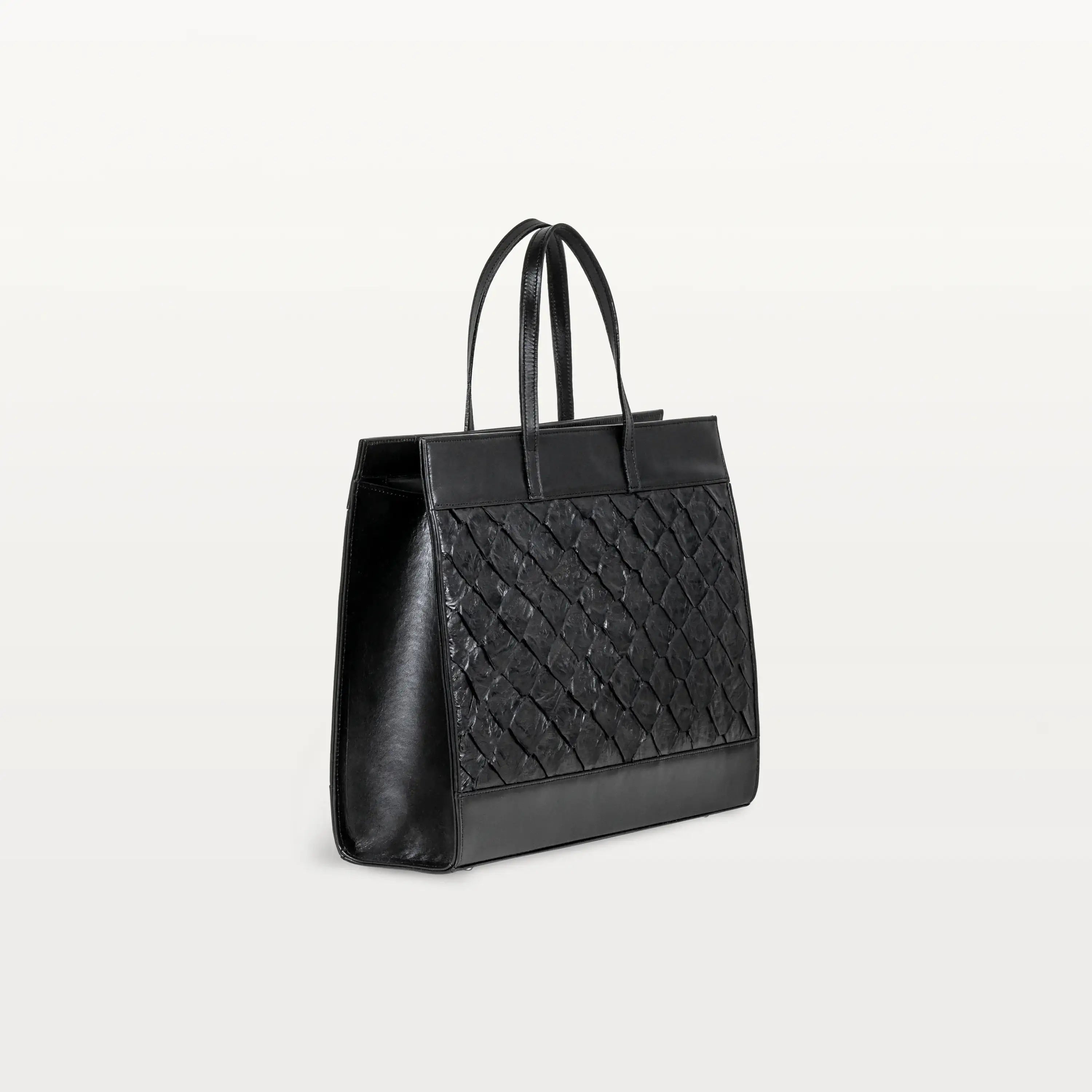 Gusseted side of the Braemar tote bag in black pirarucu leather with the top handles up.