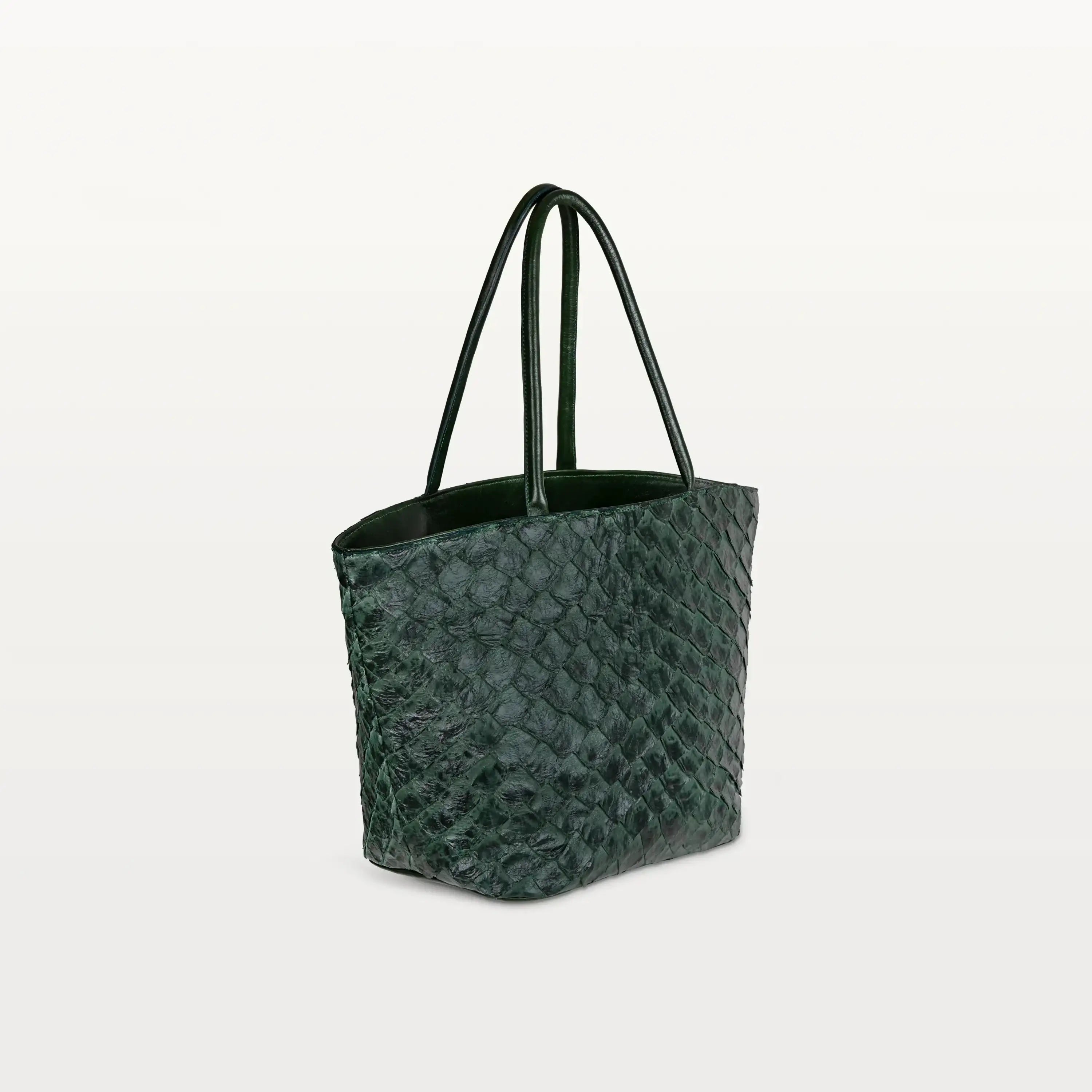 Side view of the spacious Delray Shopper in verdant green pirarucu leather, a large tote bag with a unique fish scale texture and two top handles.