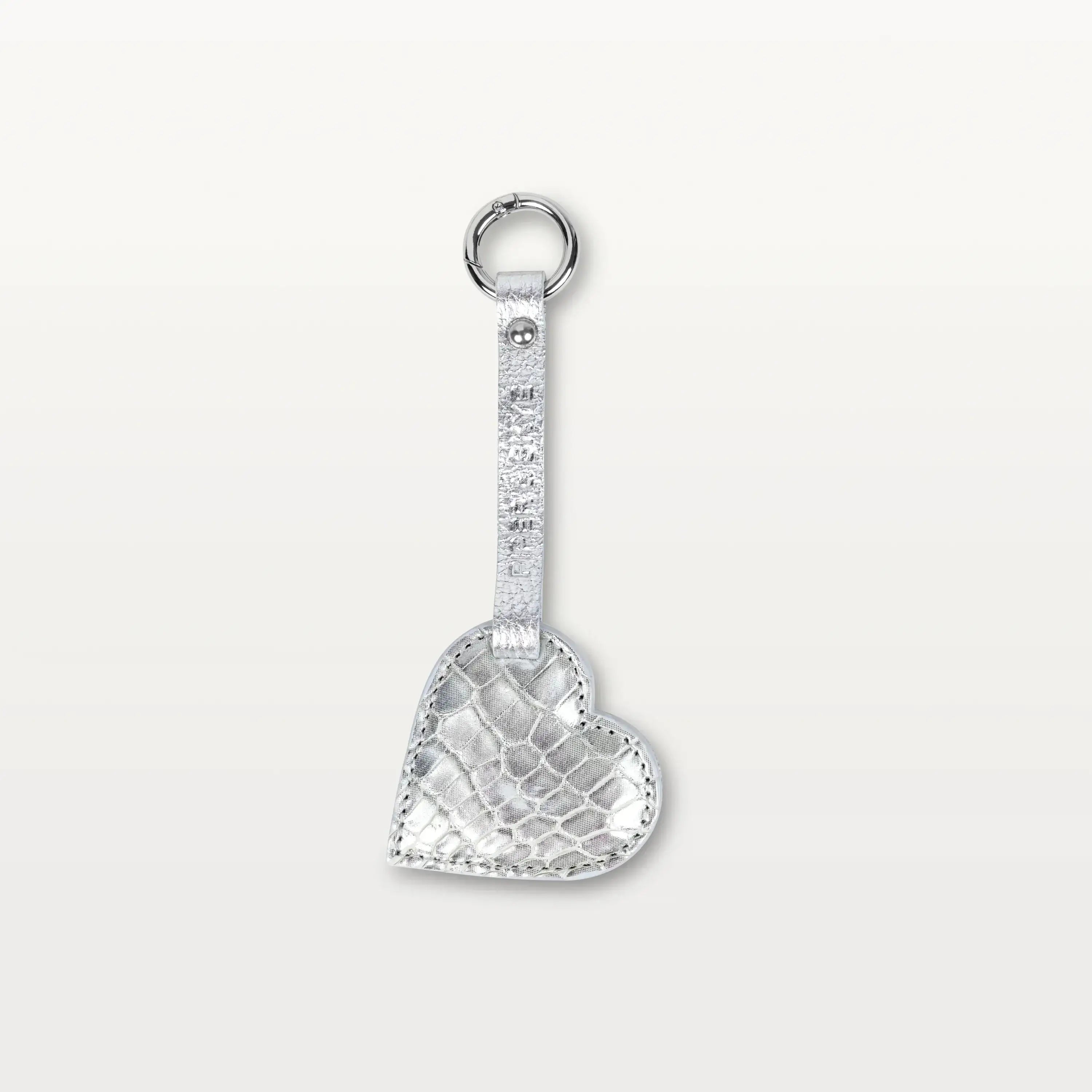 A heart-shaped keychain made from silver alligator leather hanging from a thin leather strap with a silver metallic ring.