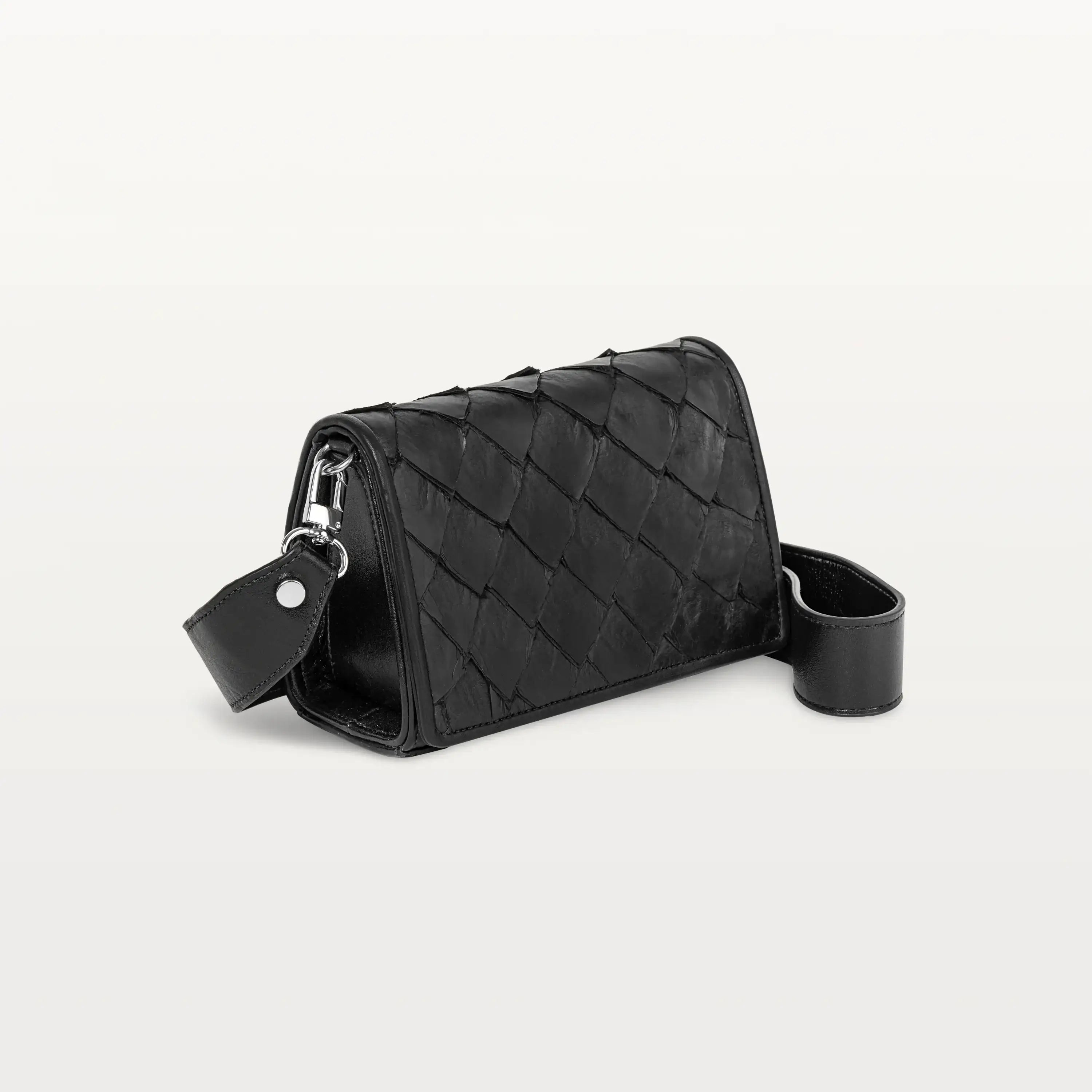 Side view of the black Lola crossbody bag in scale-like pirarucu fish leather with thick detachable strap and silver hardware