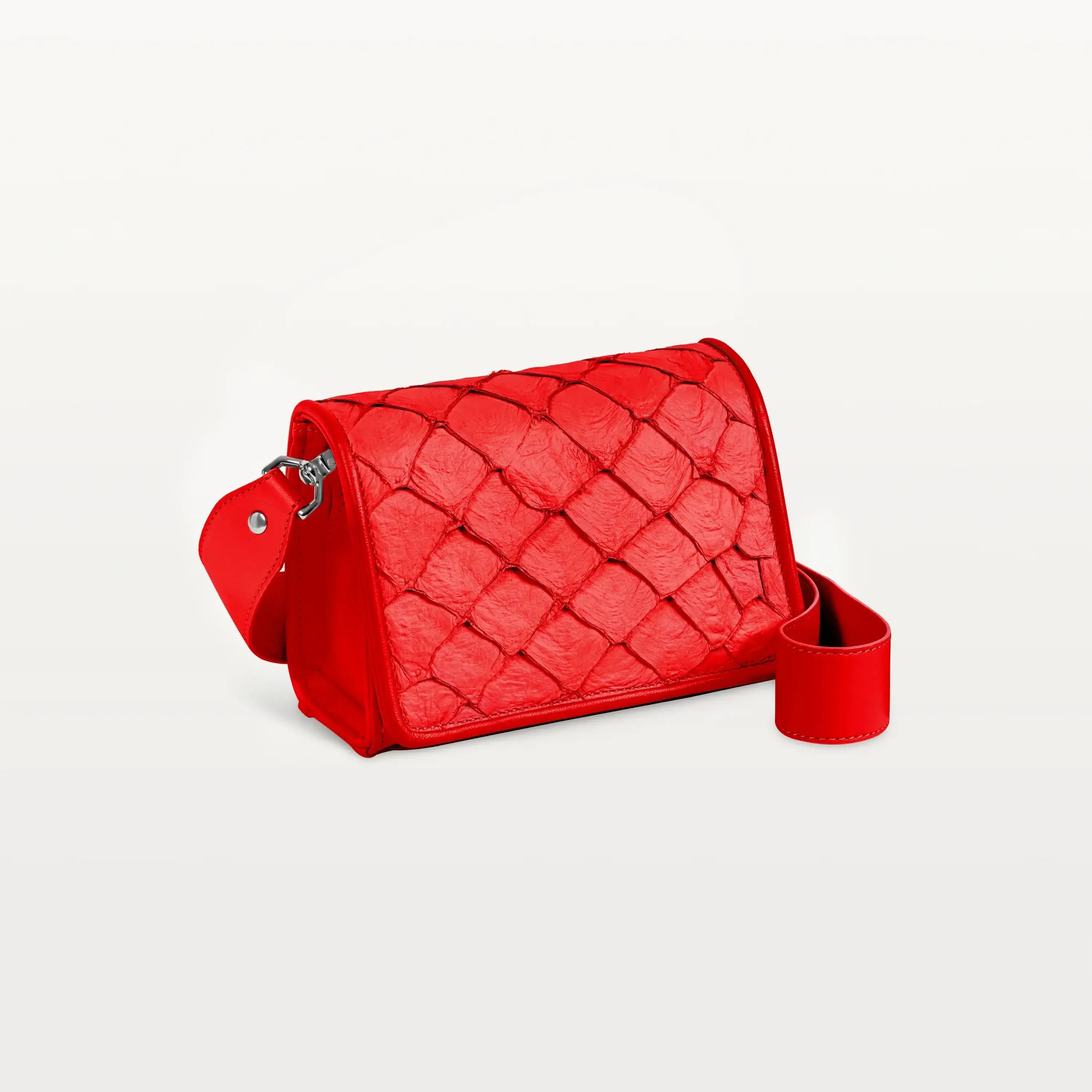 Side view of the rectangular red Lola crossbody bag in scale-like pirarucu fish leather with thick detachable strap and silver hardware