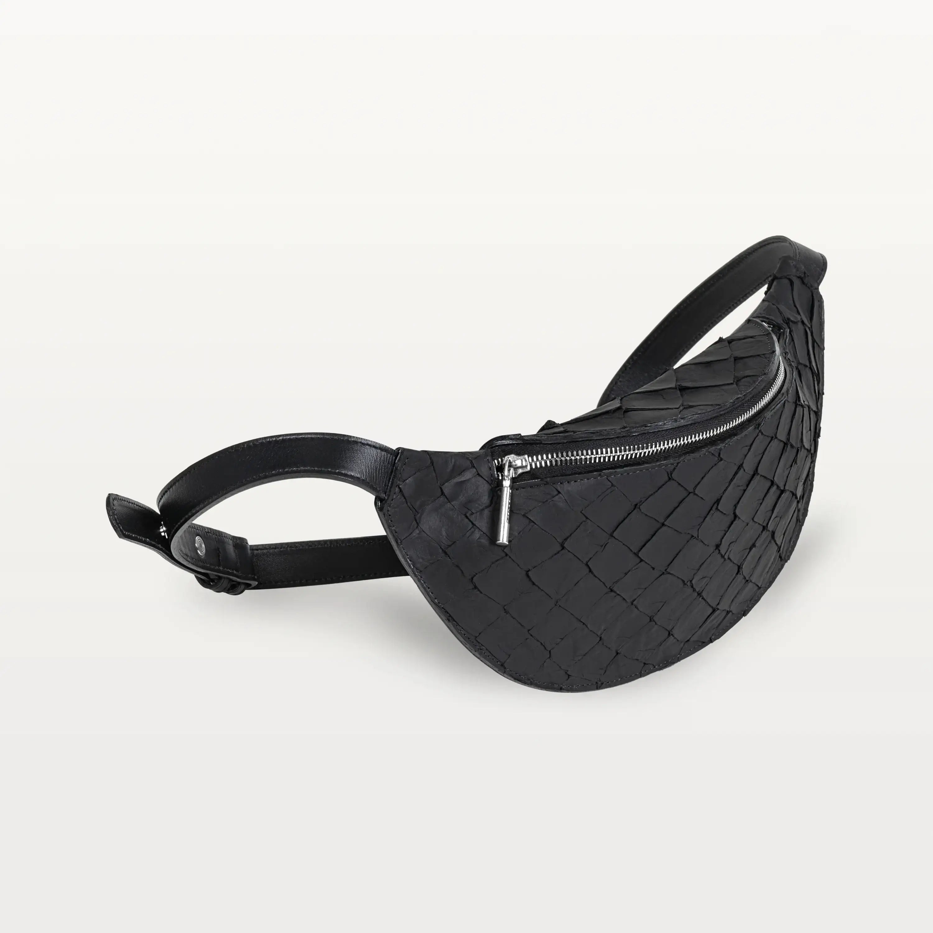 Side view of the Mac Pack belt bag in black pirarucu fish leather showing the tapered body and adjustable leather belt strap.