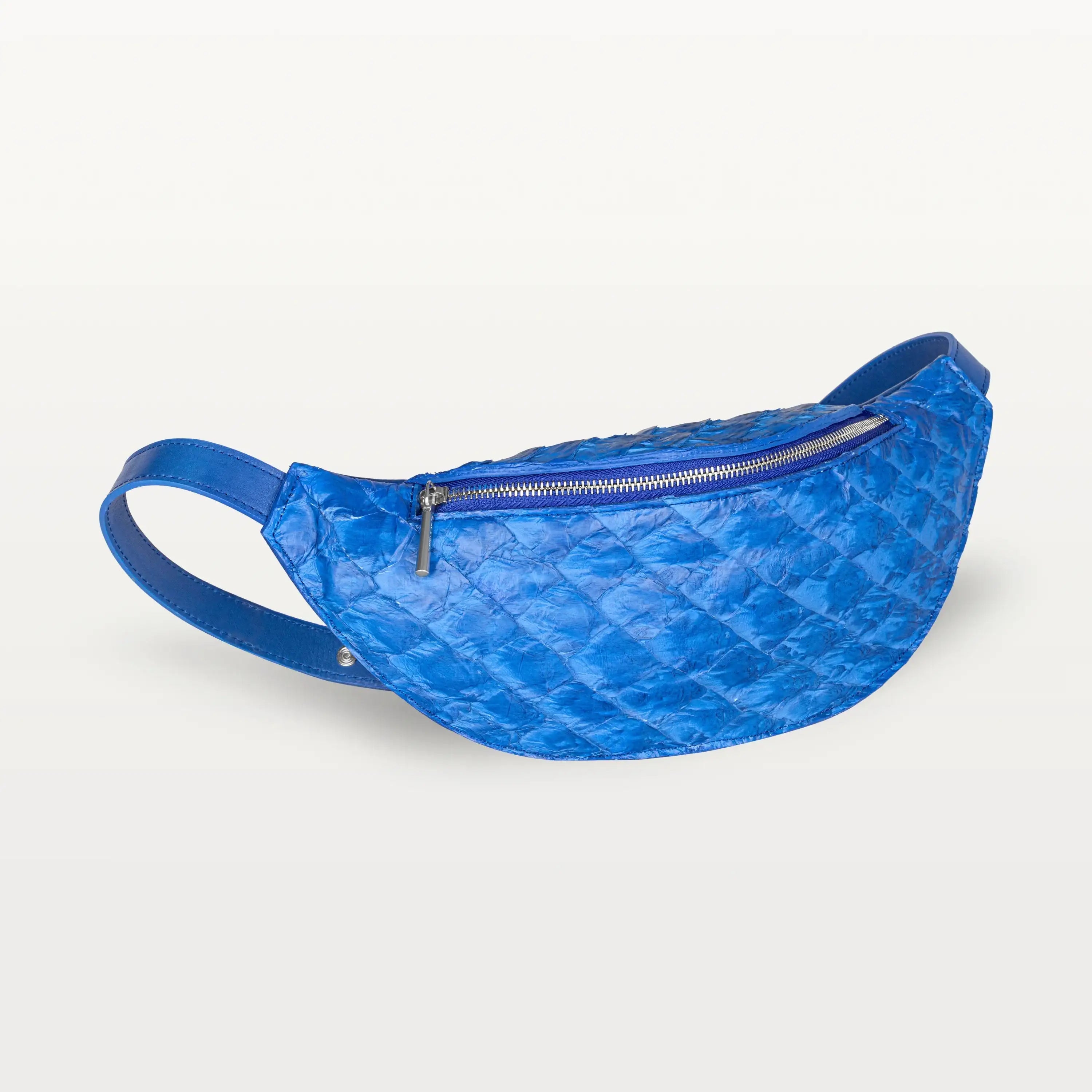 Side view of the Mac Pack belt bag in cobalt blue pirarucu fish leather showing the tapered body and adjustable leather belt strap.