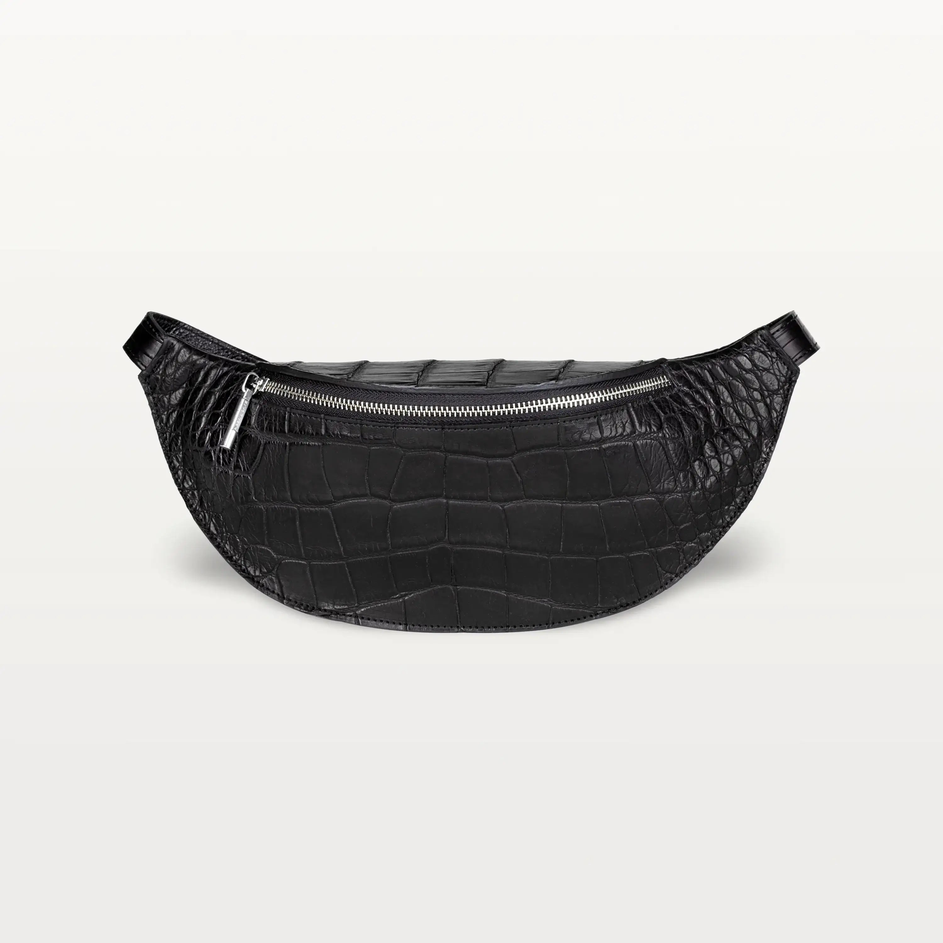 Front view of the Mac Pack belt bag in glossy black alligator leather with a silver zipper and curved body shape.