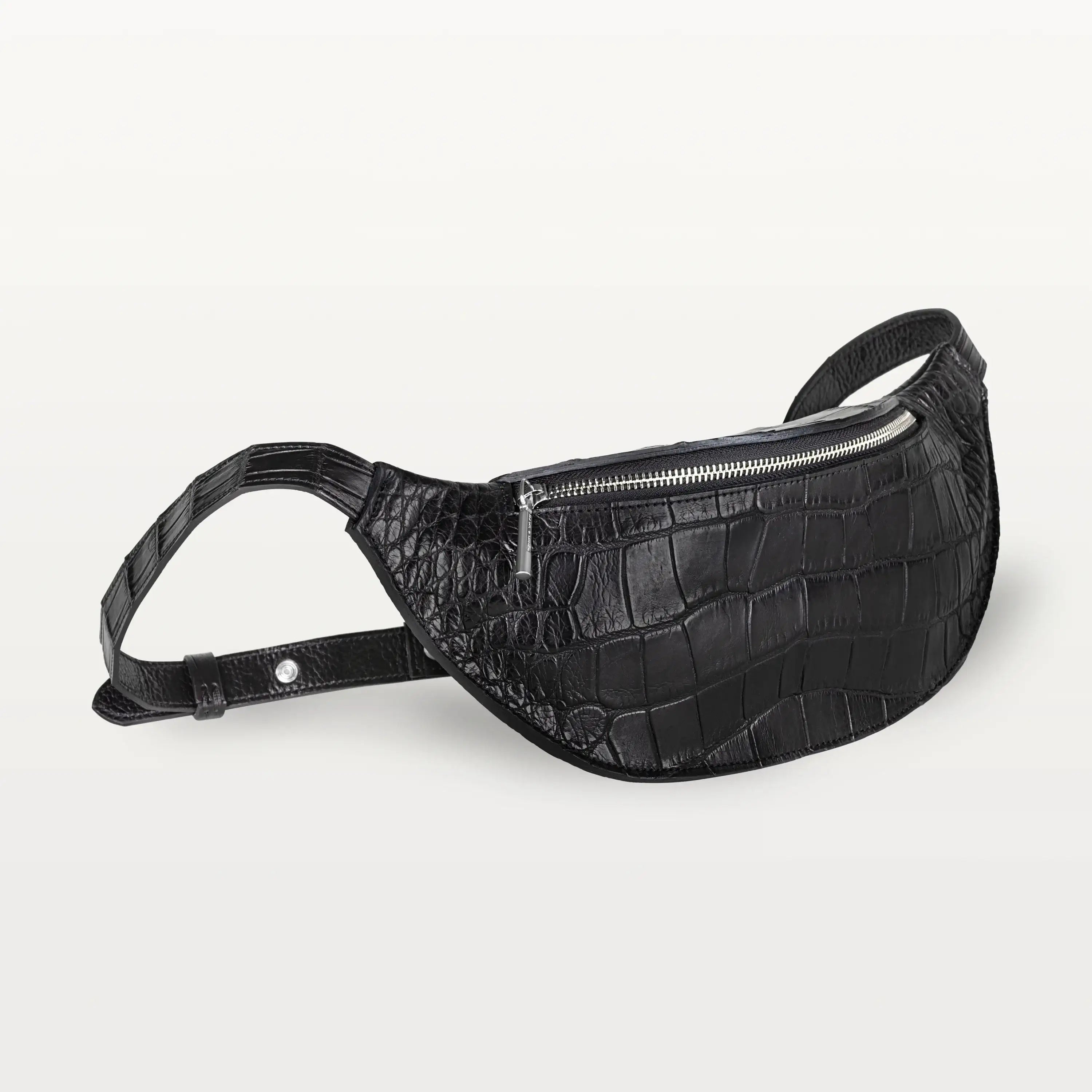 Side view of the Mac Pack belt bag in glossy black alligator leather showing the tapered body and adjustable leather belt strap.