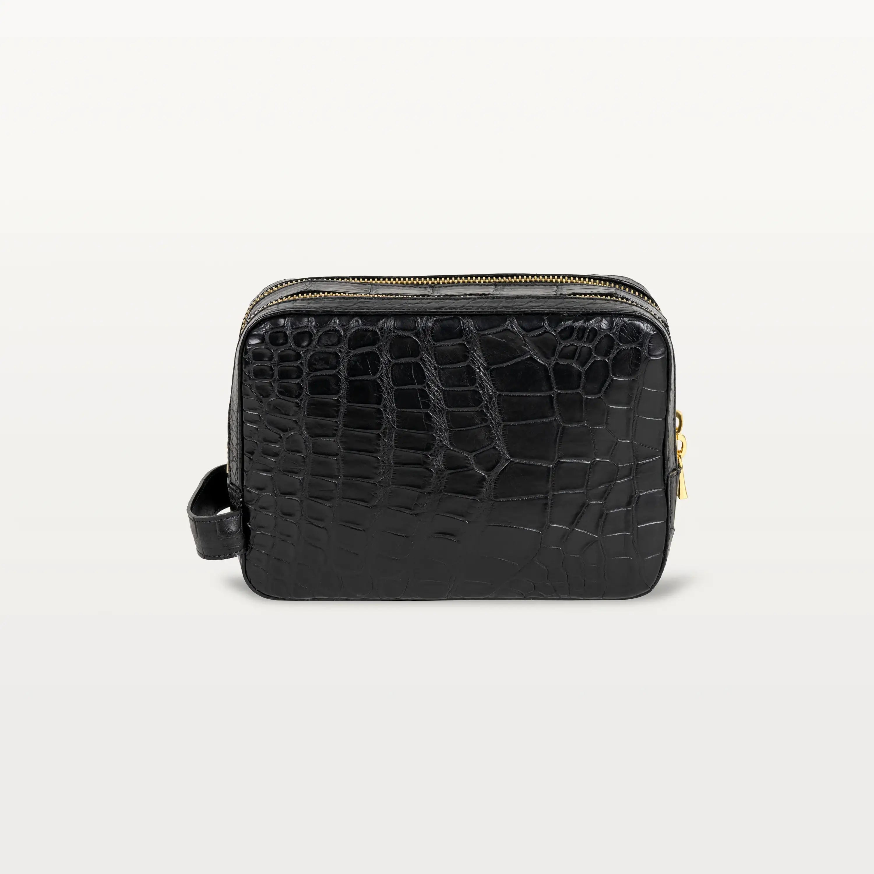 The structured rectangular Nomad Dopp Kit in glossy black alligator with a side handle for easy carrying.