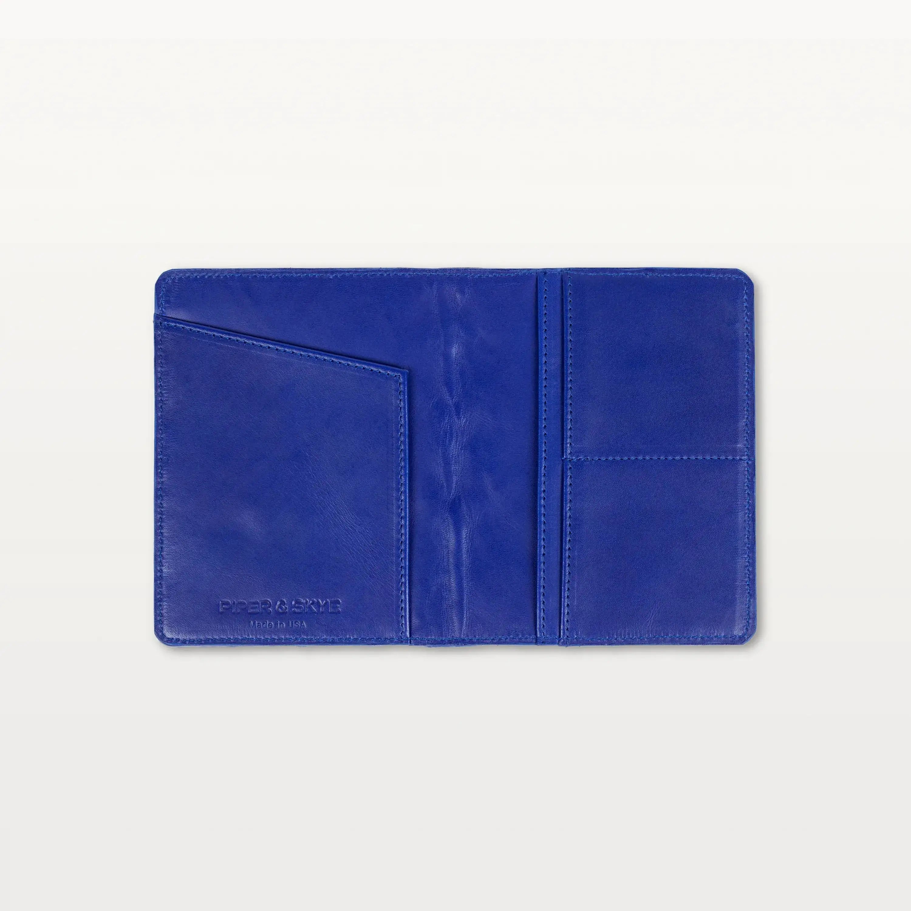 Open view of the cobalt blue pirarucu leather passport holder showing the leather interior and slip pockets.