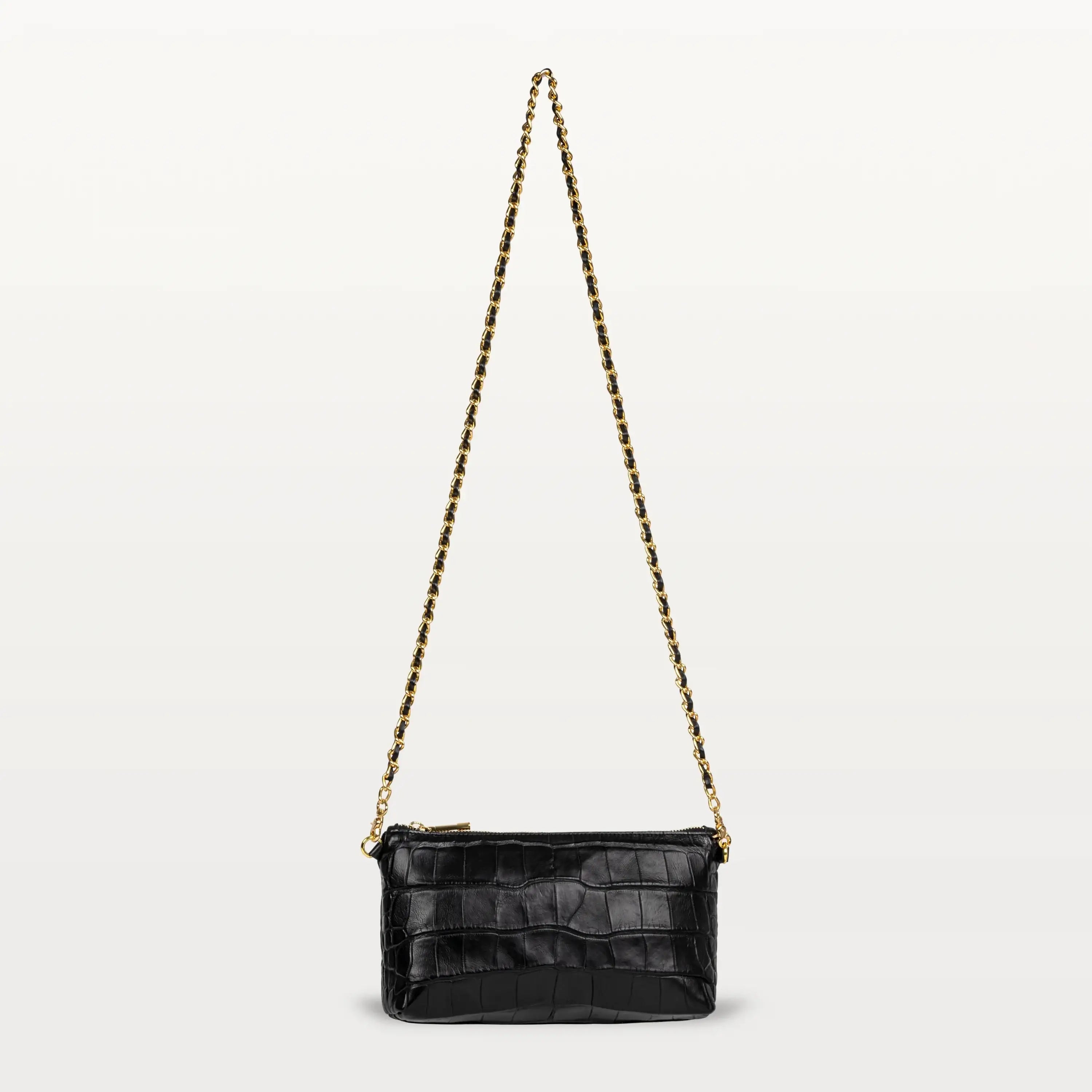 A small rectangular crossbody bag made from glossy black alligator with a long gold and black chain strap and gold zipper.
