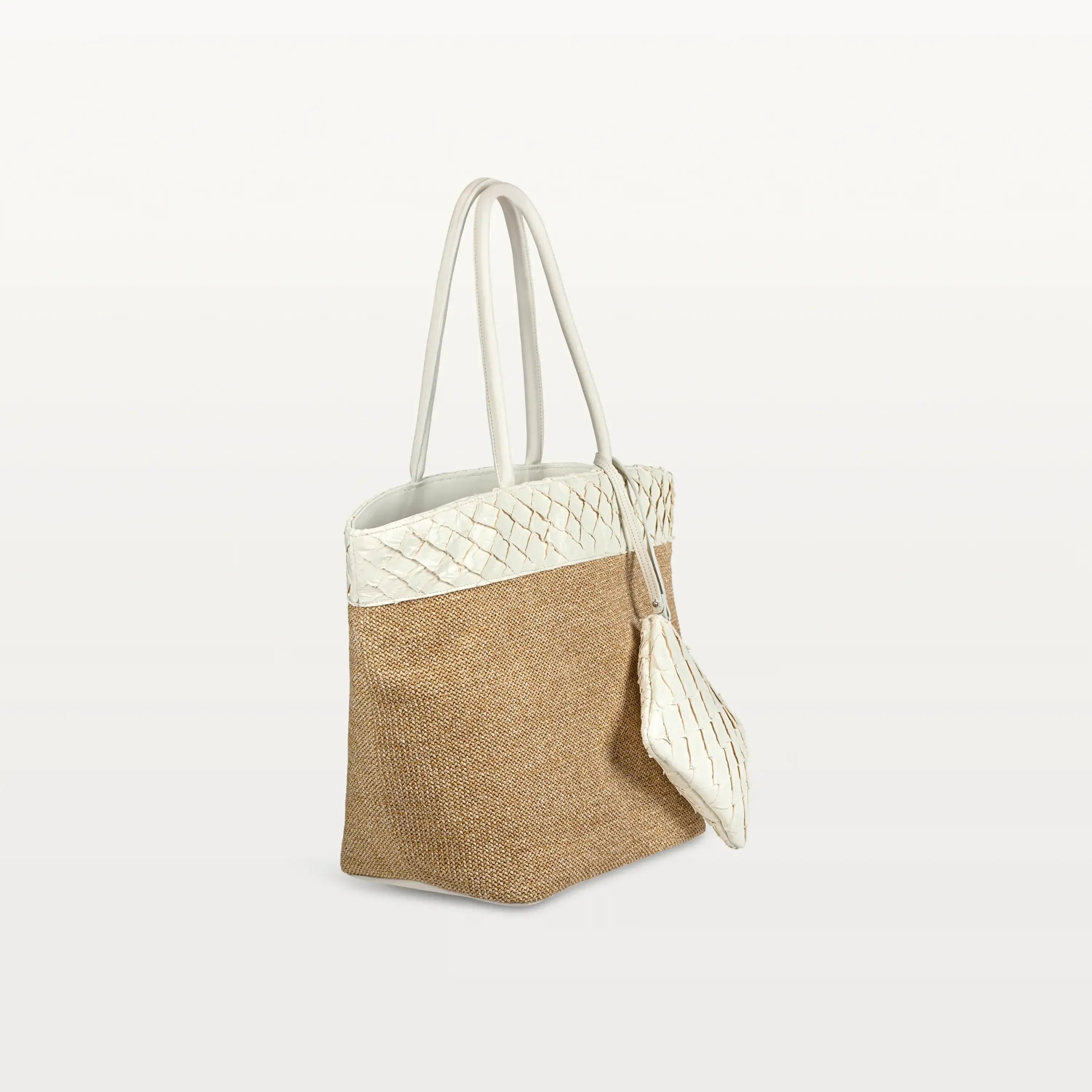 Side view of the Rio Beach Bag with a camel raffia body and clay white pirarucu leather trim. A matching clay white pirarucu leather wristlet hangs from the strap