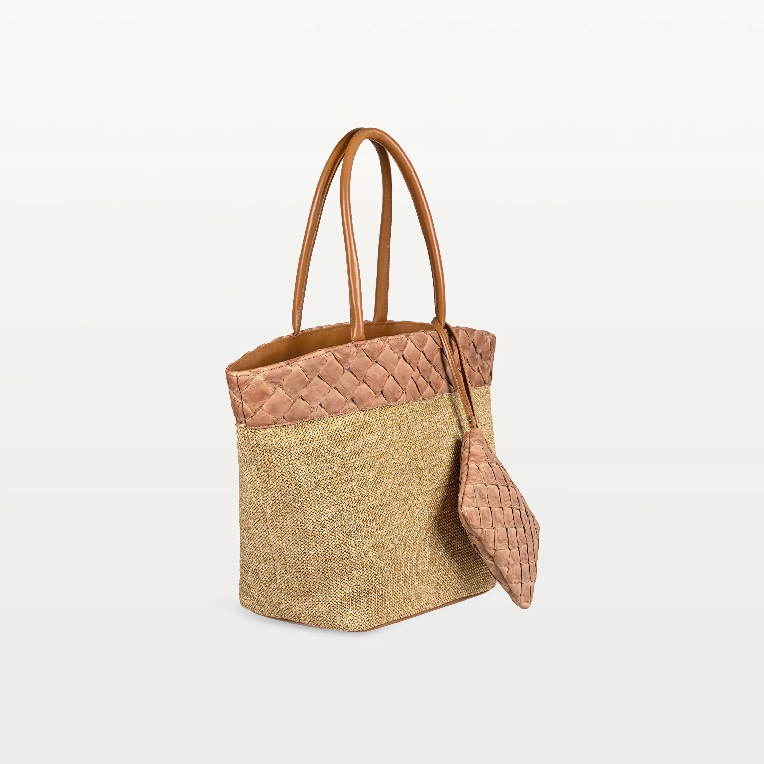 Side view of the Rio Beach Bag with a camel raffia body and cognac pirarucu leather trim. A matching cognac pirarucu leather wristlet hangs from the strap