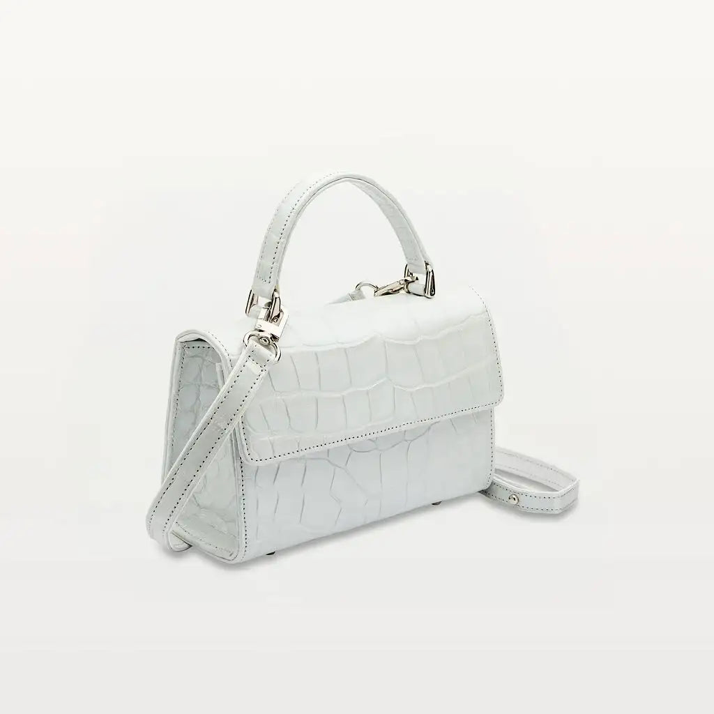 Side view of Piper & Skye's sustainable leather Soho Top Handle crossbody handbag in Moonstone White.