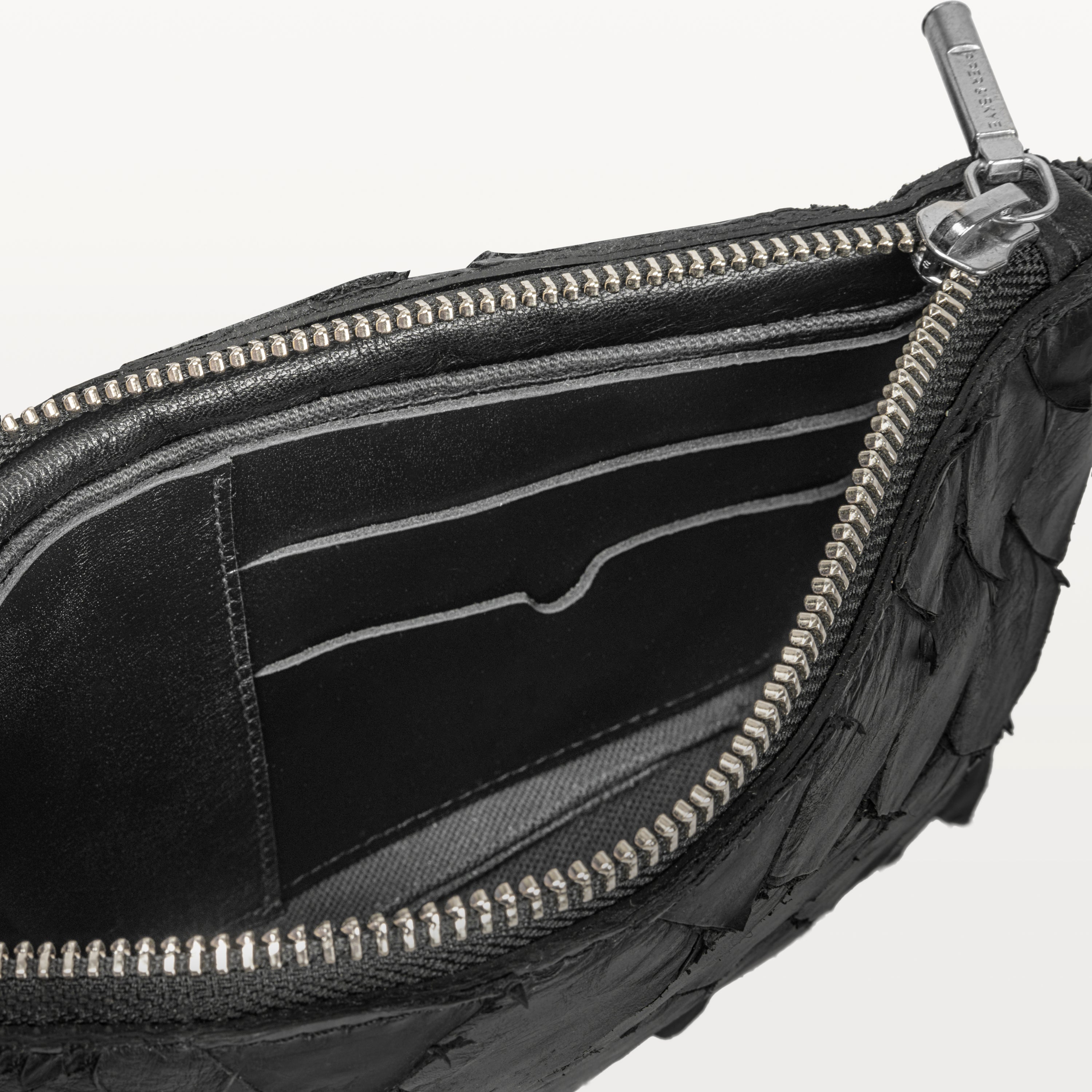 Interior of the black pirarucu fish leather crossbody bag showing card slots and the silver top zipper. 
