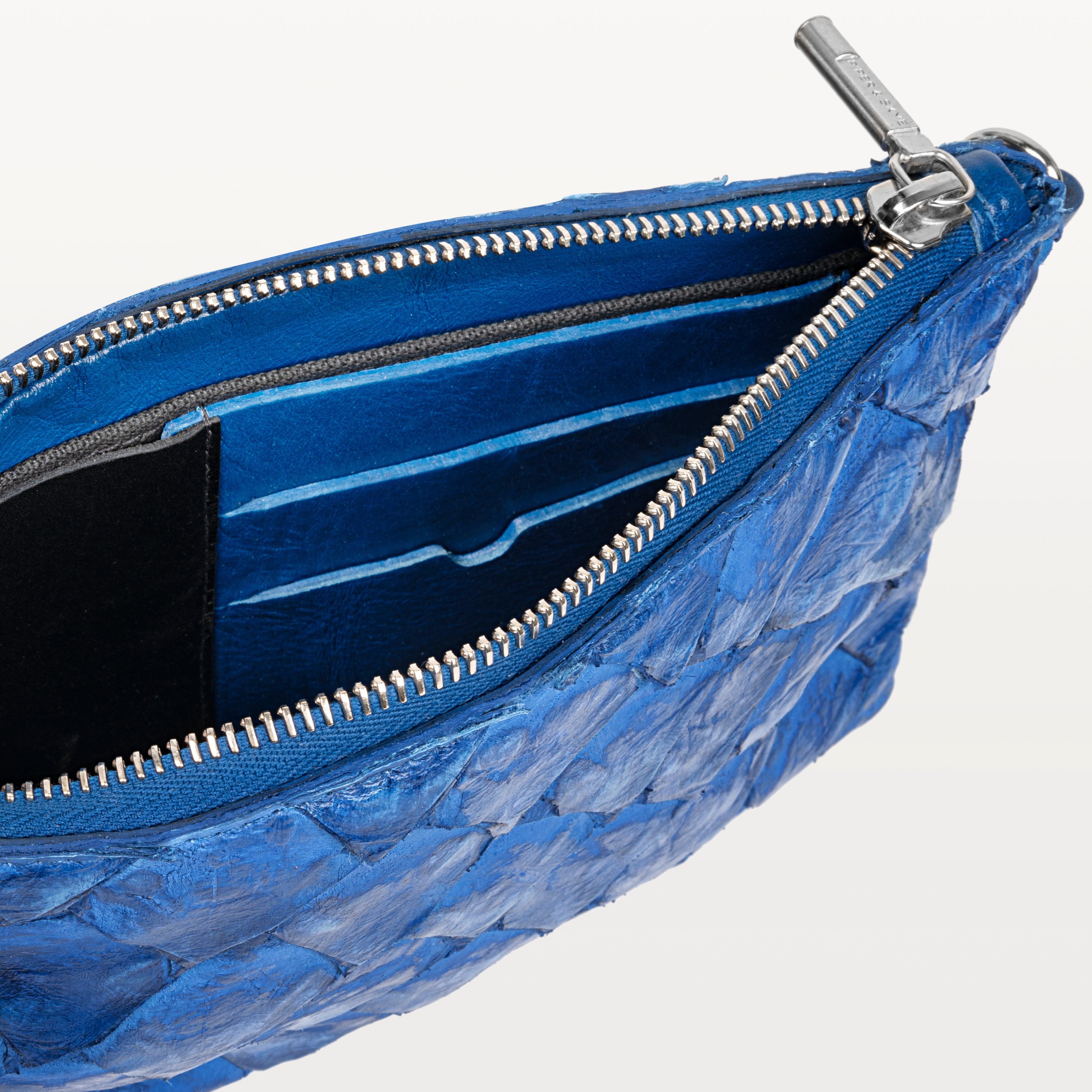 Interior of the sustainable cobalt blue pirarucu fish leather crossbody bag showing card slots and the silver top zipper. 