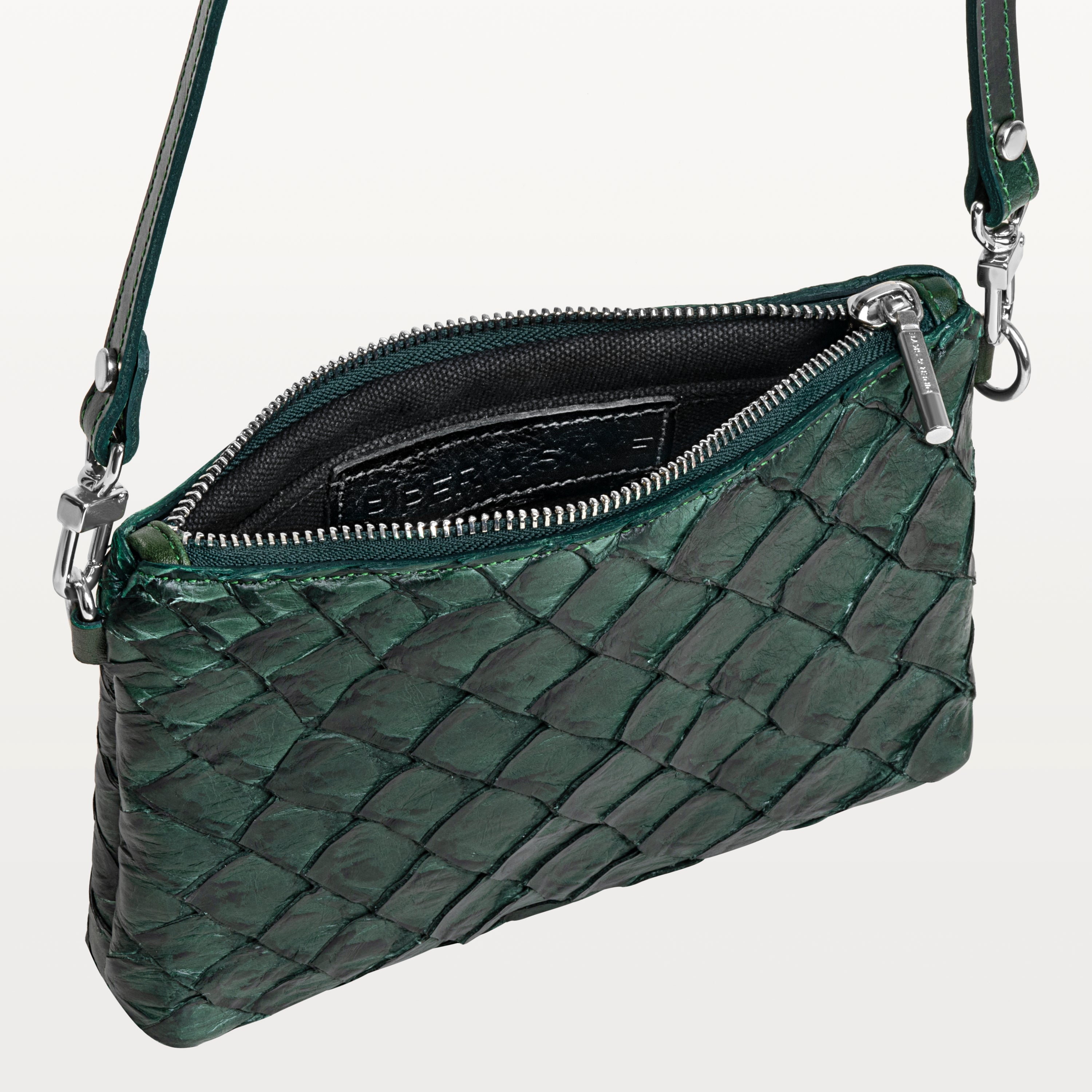 Small verdant green crossbody bag made of pirarucu leather with its silver top zipper open revealing the black interior and Piper & Skye logo. 