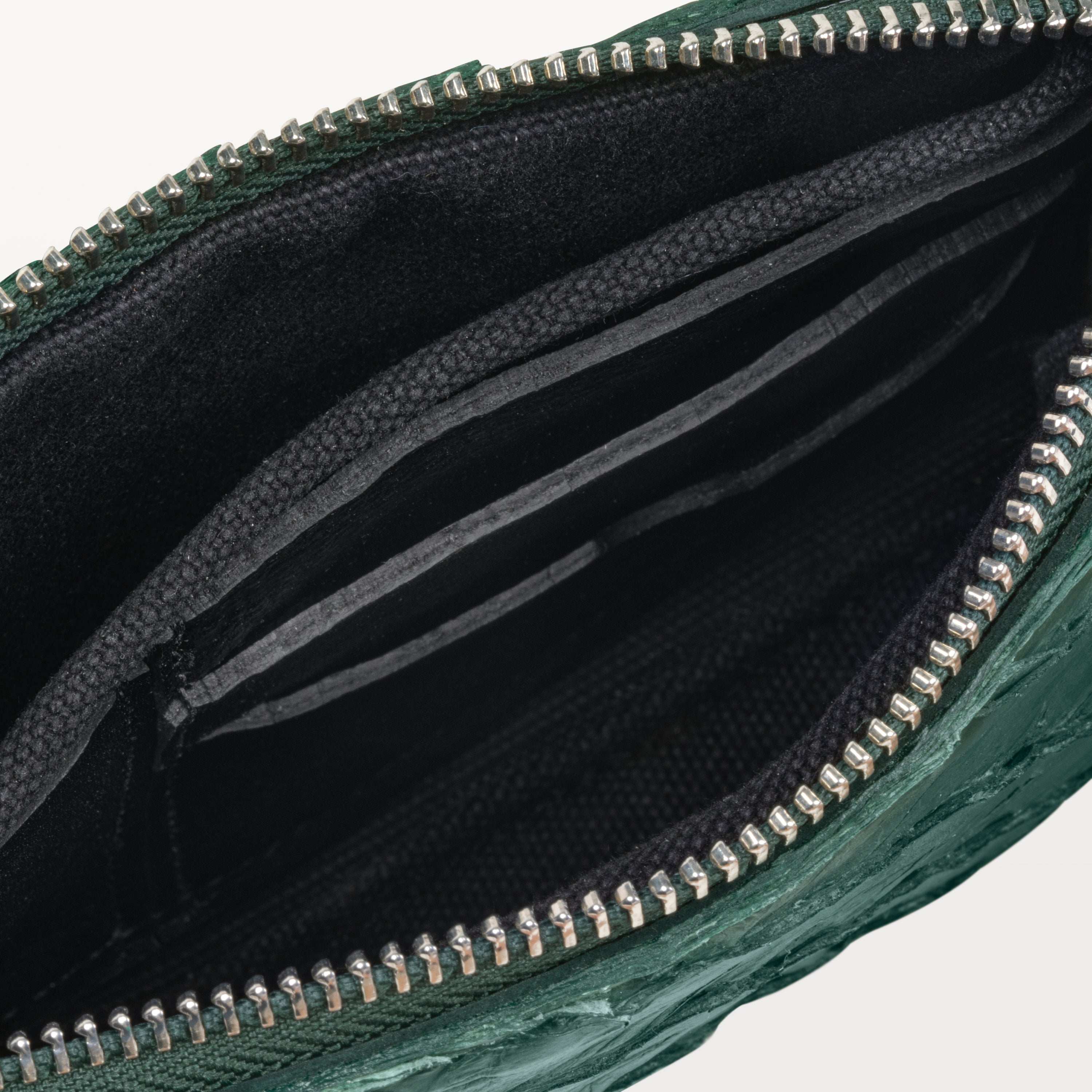 Interior of the sustainable verdant green pirarucu fish leather crossbody bag showing black card slots and the silver top zipper. 