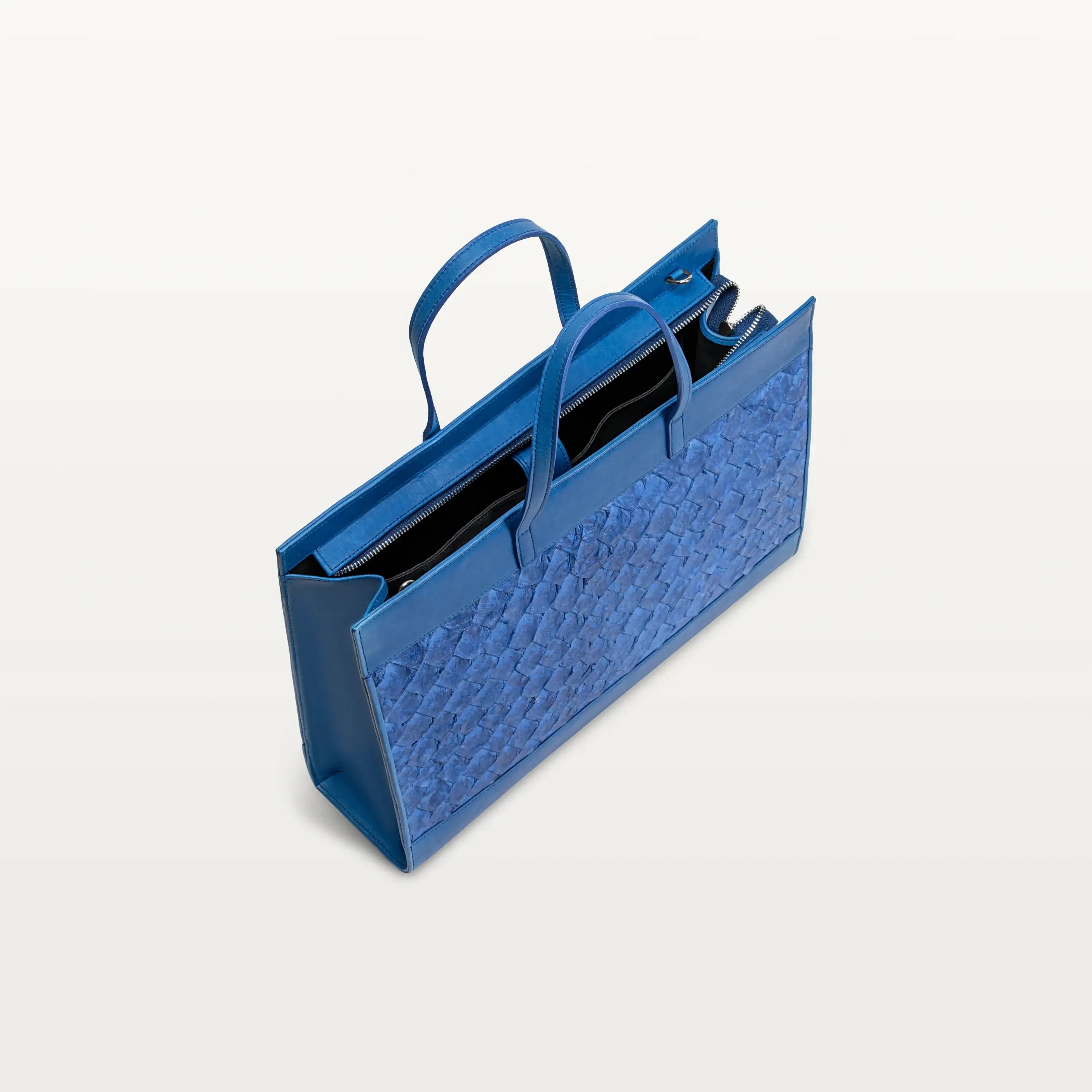Braemar tote bag in cobalt blue pirarucu leather with the top zipper open showing the black interior. 