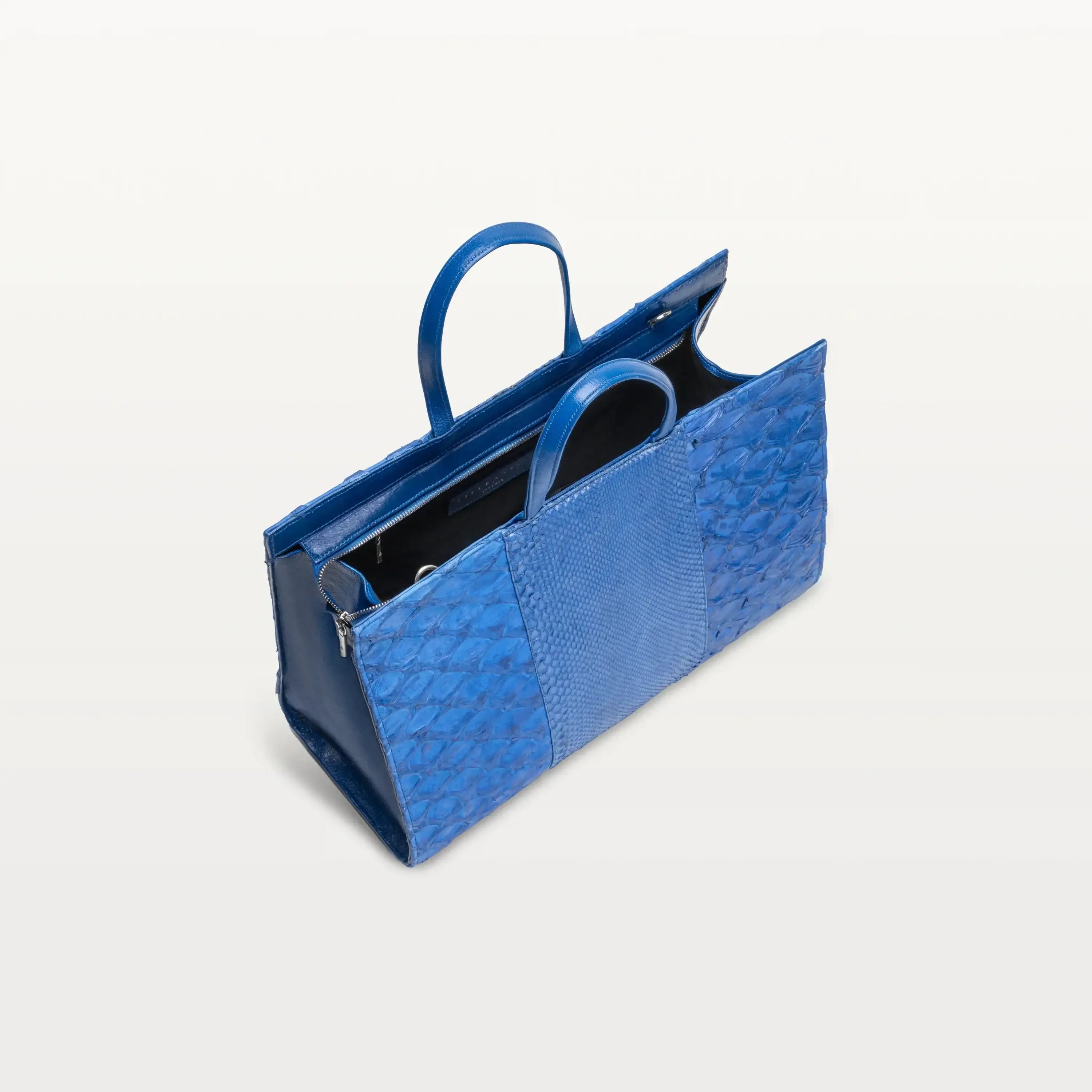 Braemar tote bag in cobalt blue python and pirarucu leather with the top zipper open showing the black interior. 