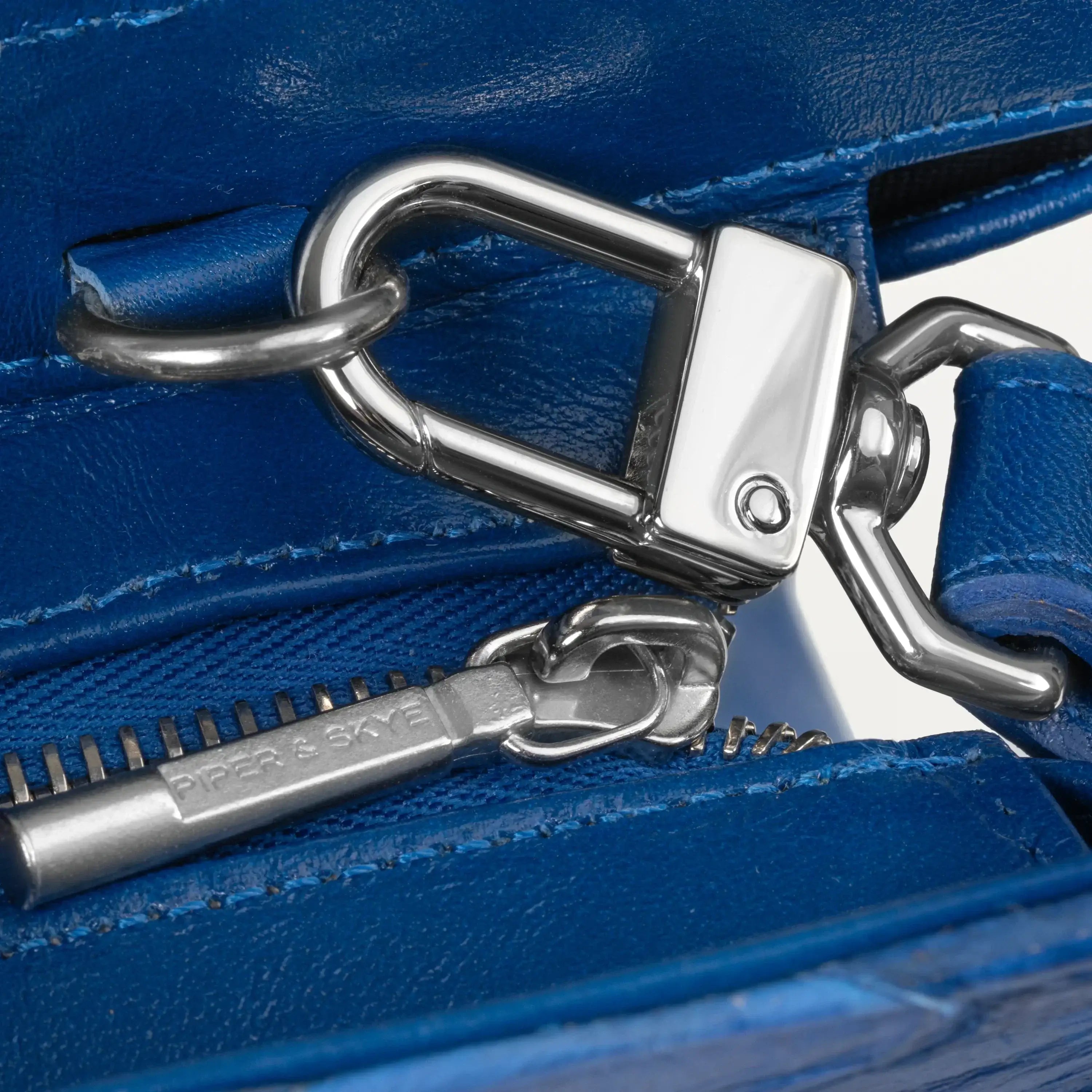 Silver crossbody strap hardware and top zipper pull of the Braemar tote bag in cobalt blue python and pirarucu leather. 