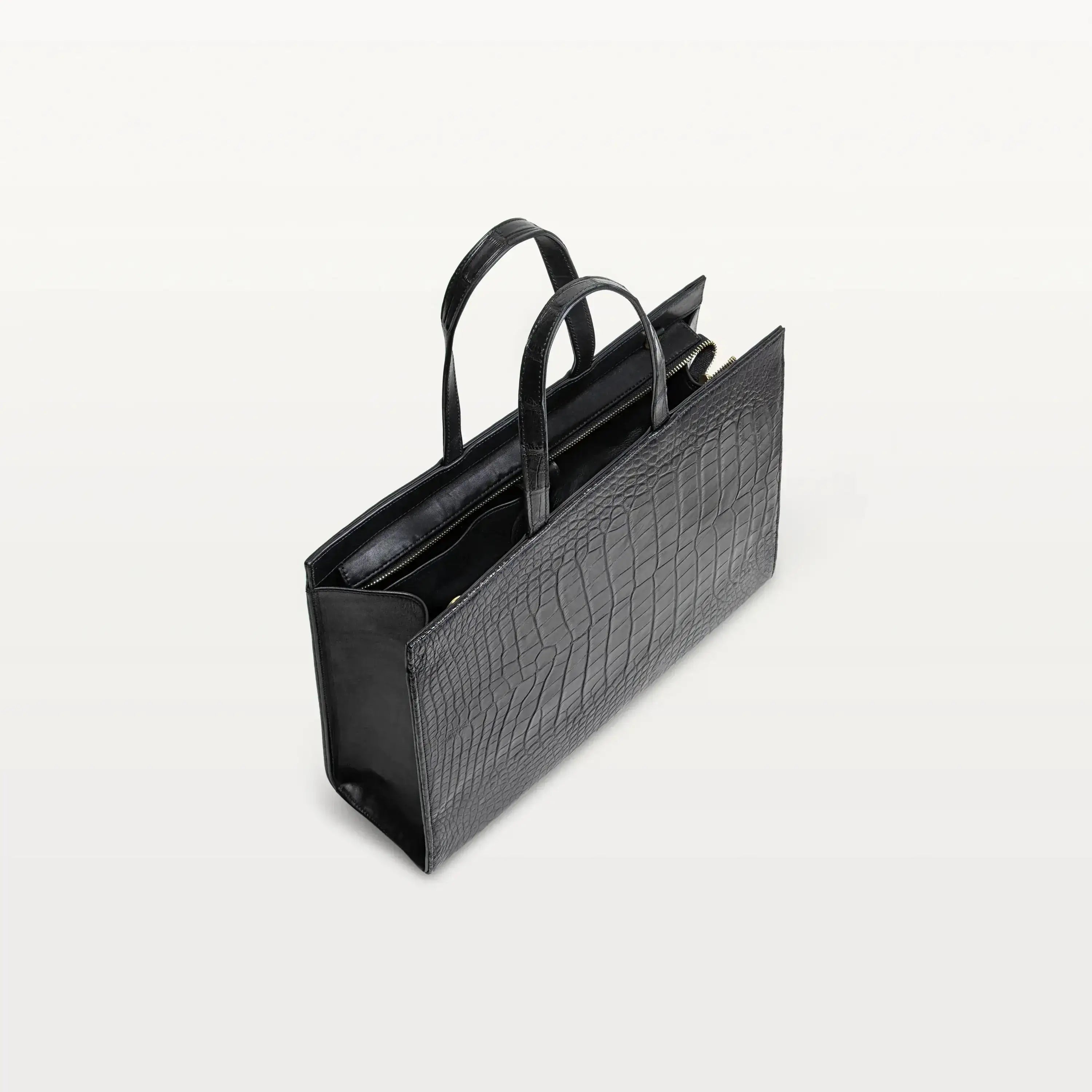 Braemar tote bag in black alligator leather with the top zipper open showing the black interior. 