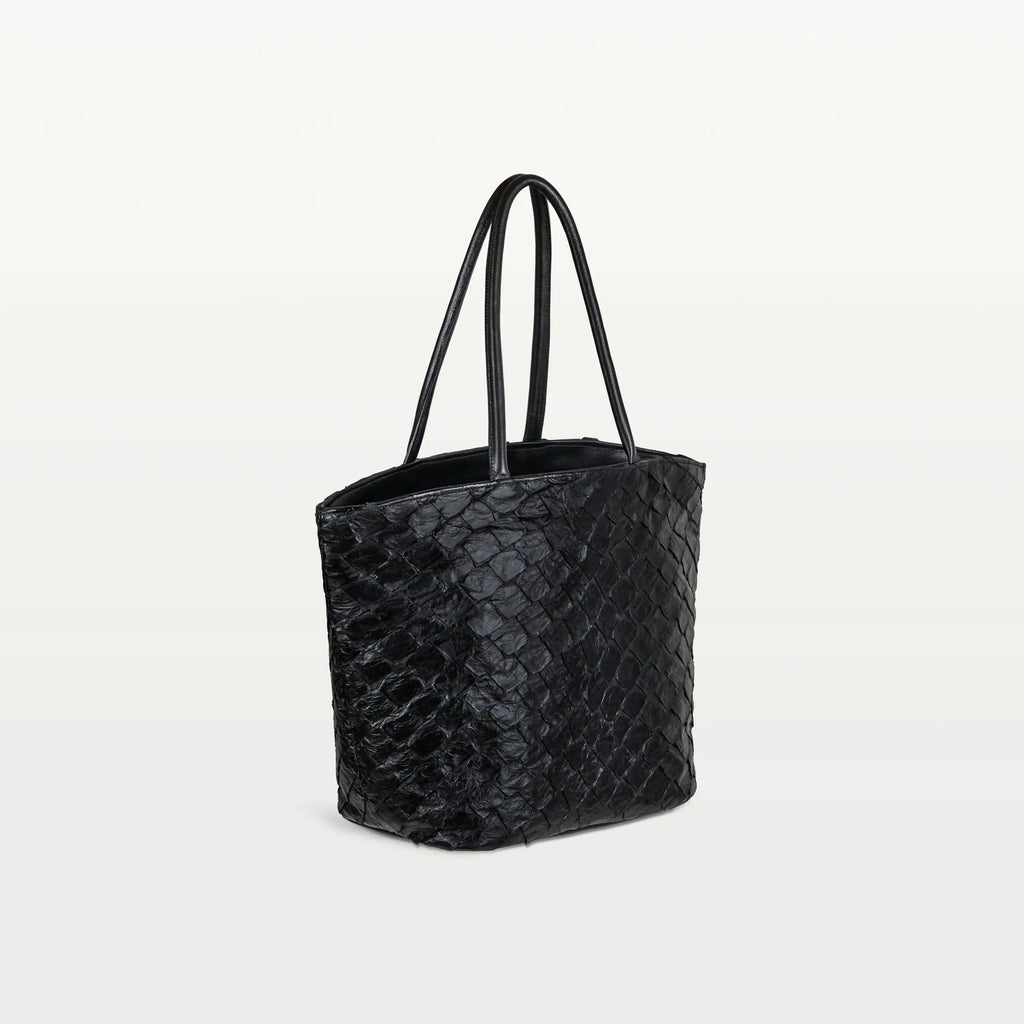 Side view of the spacious Delray Shopper in black pirarucu leather, a large tote bag with a unique fish scale texture and two top handles. 