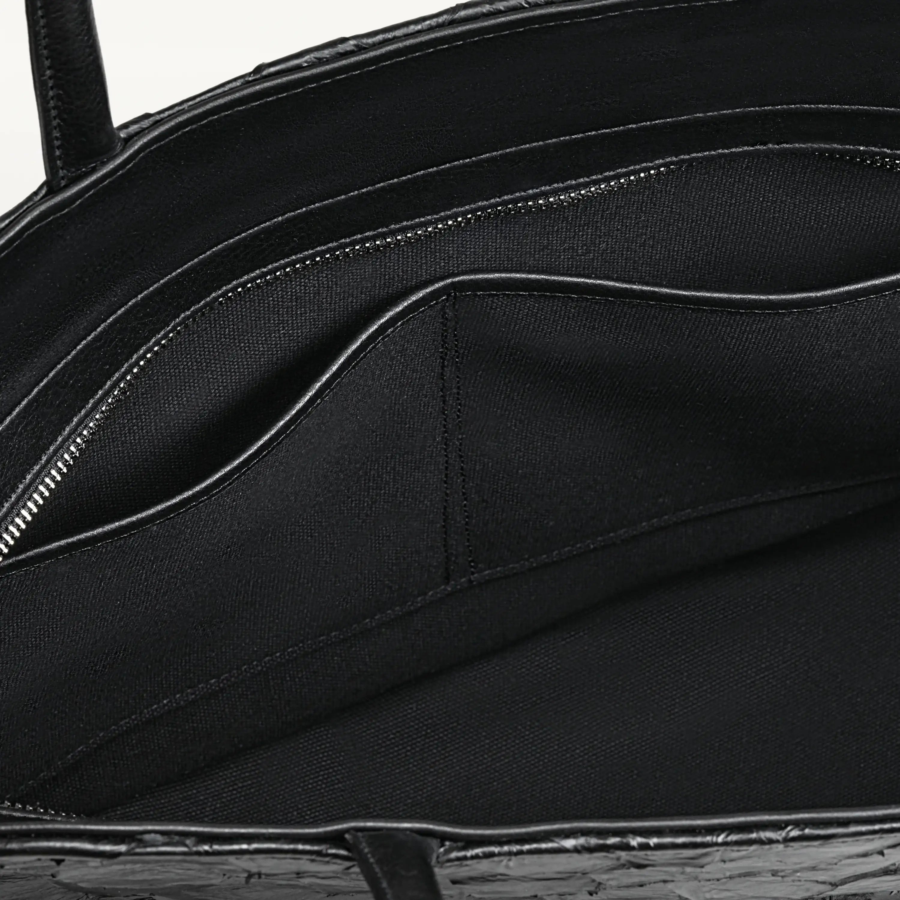 Top zipper of the black Delray tote bag opened to show the black interior lining and two inner slip pockets. 