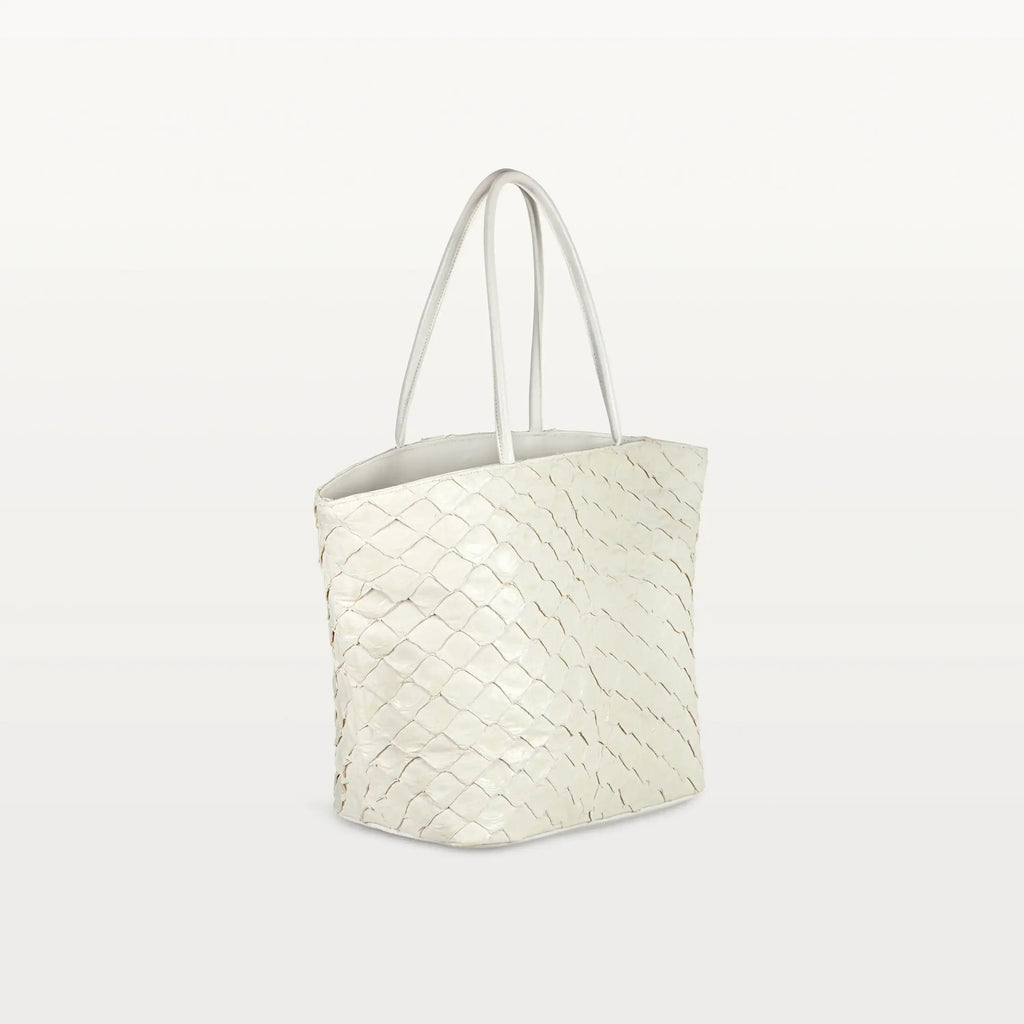 Side view of the spacious Delray Shopper in clay white pirarucu leather, a large tote bag with a unique fish scale texture and two top handles. 