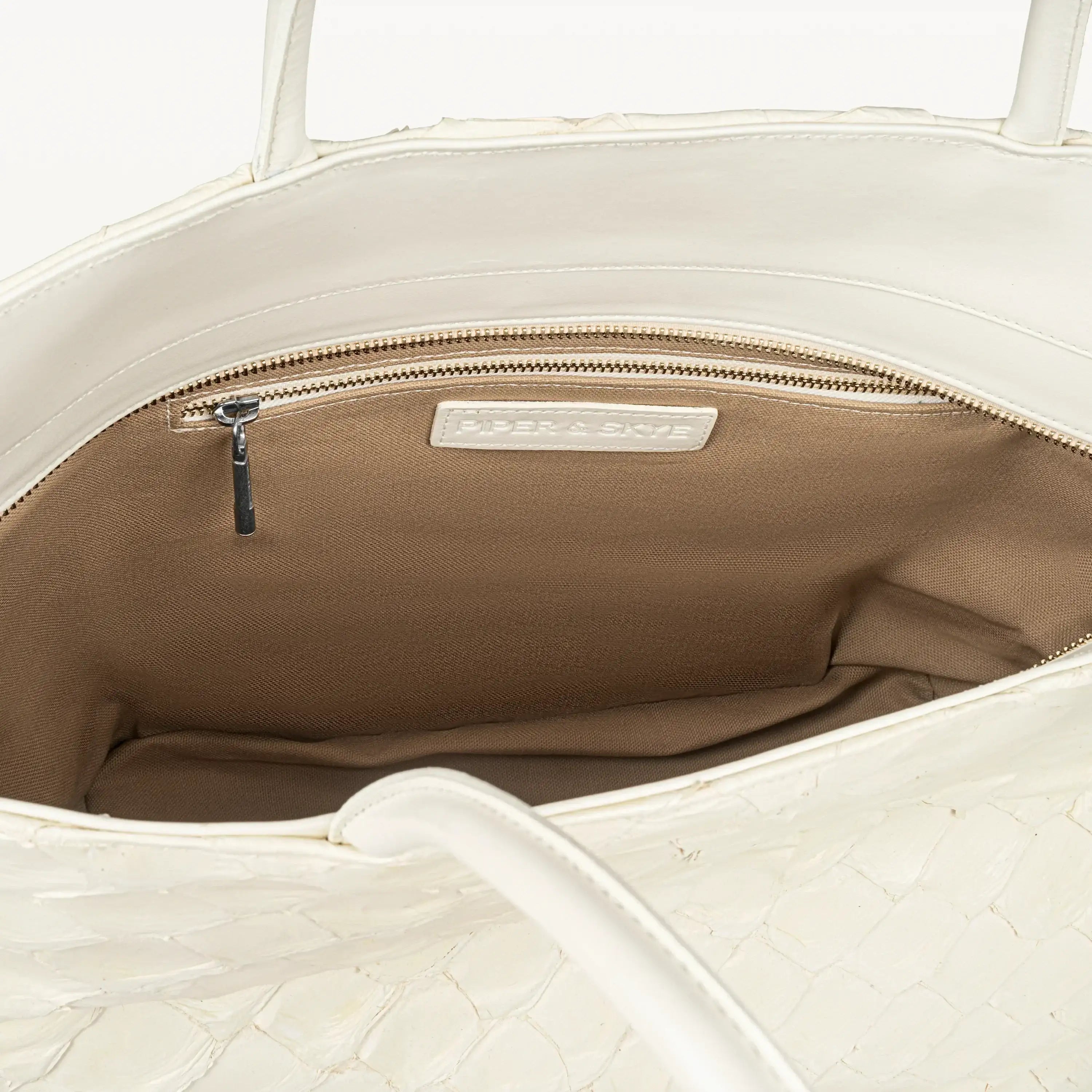 Delray shopper tote bag in clay white pirarucu leather opened to show the beige interior lining and inner zipper pocket. 