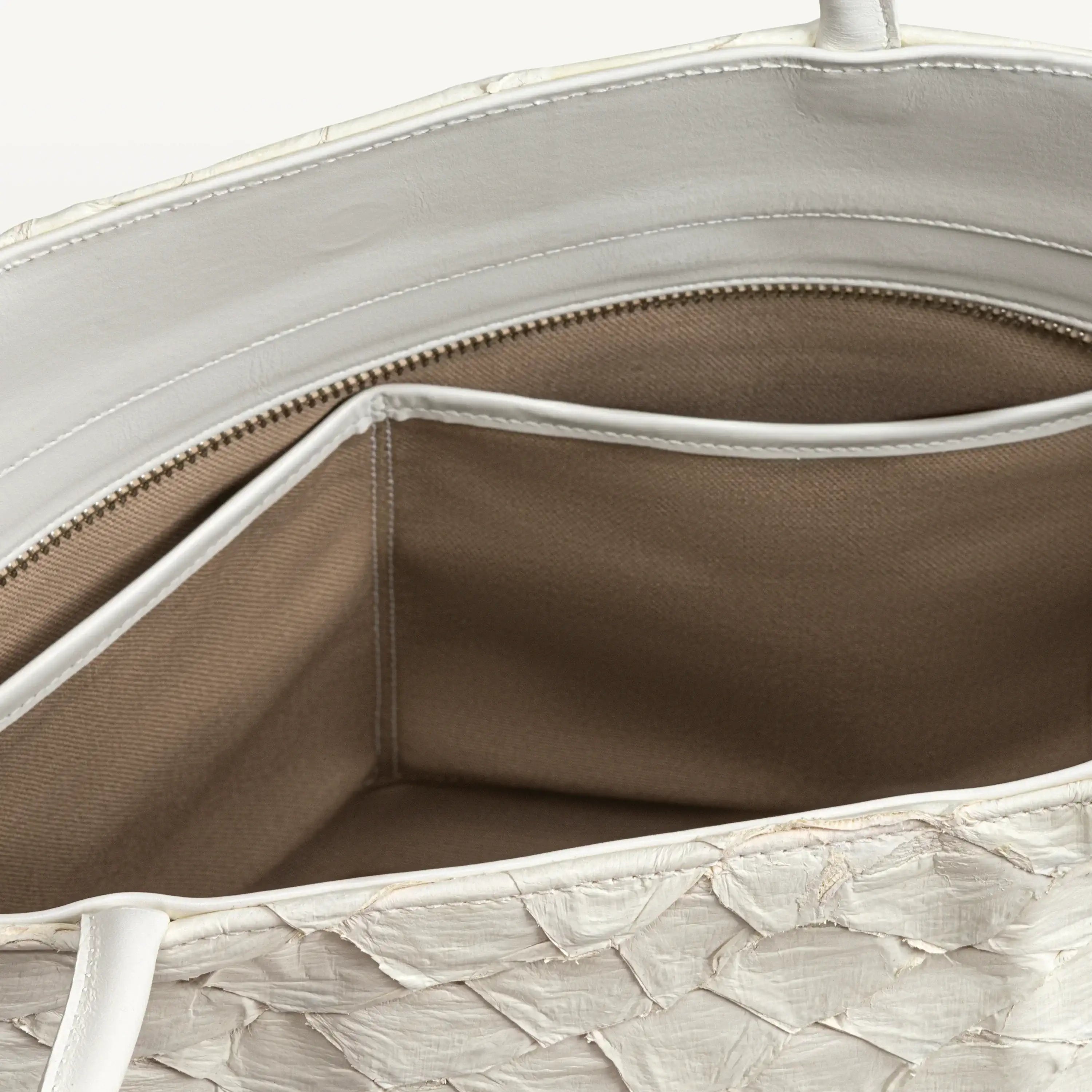 Top zipper of the clay white Delray tote bag opened to show the beige interior lining and two inner slip pockets. 