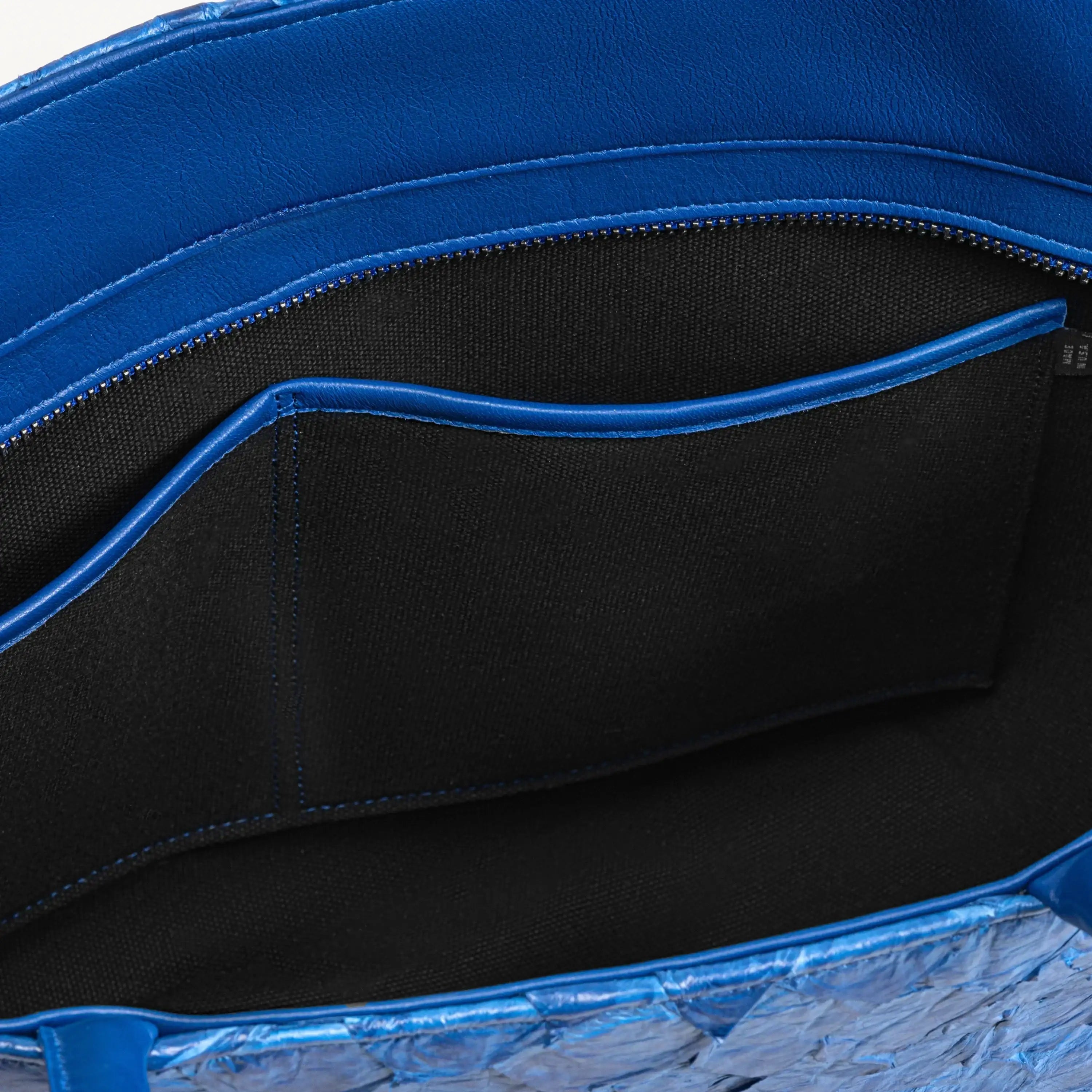 Top zipper of the cobalt blue Delray tote bag opened to show the black interior lining and two inner slip pockets. 