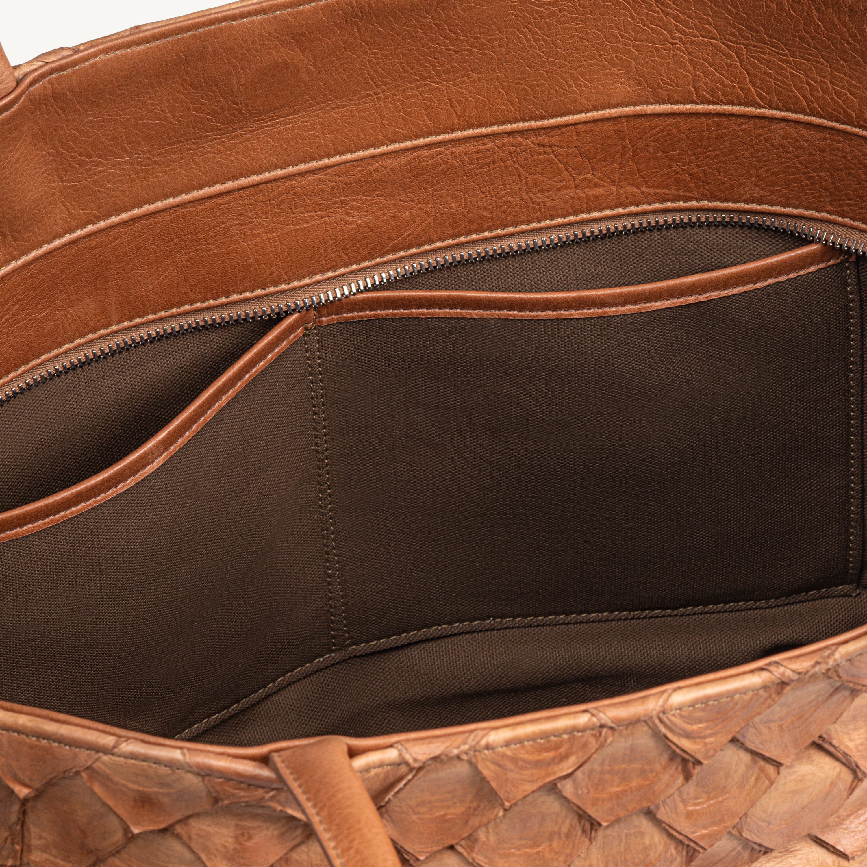 Top zipper of the cognac Delray tote bag opened to show the brown interior lining and two inner slip pockets. 