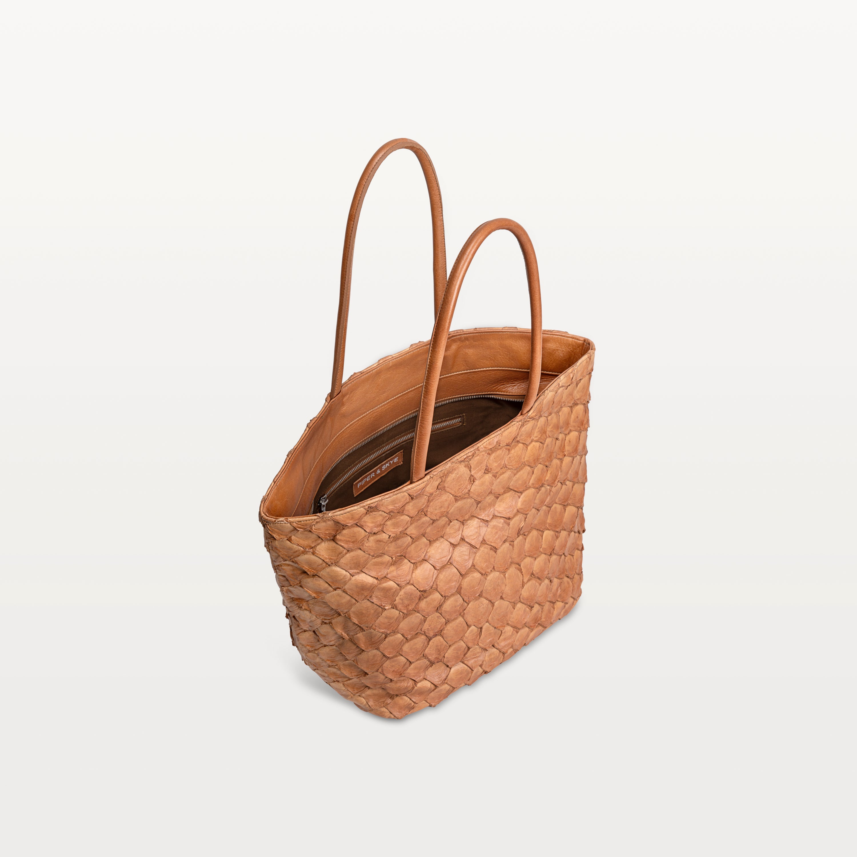 Top zipper of the Delray shopper in cognac pirarucu leather open to show the brown interior lining and inner zipper pocket.