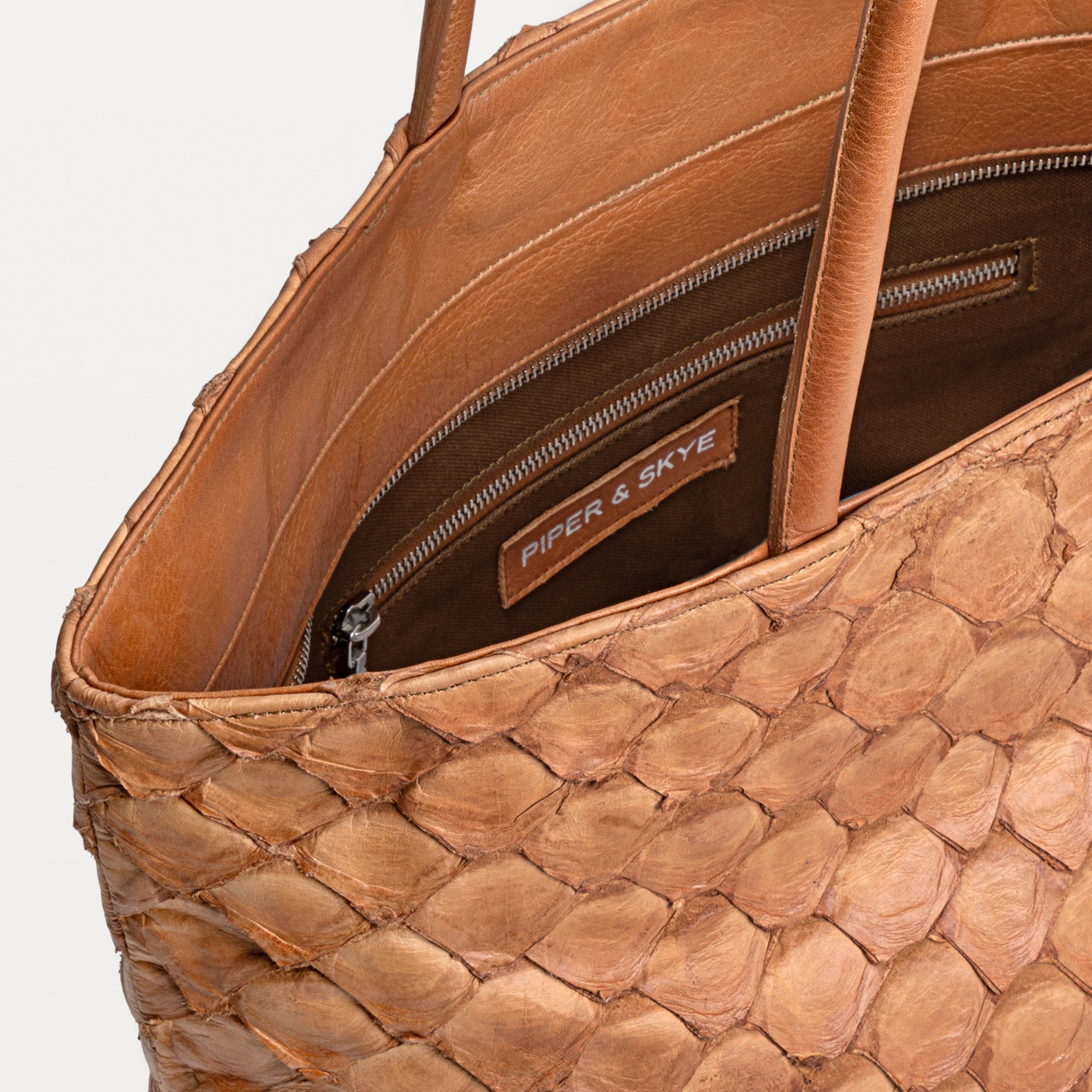 Delray shopper tote bag in cognac pirarucu leather opened to show the brown interior lining and inner zipper pocket. 