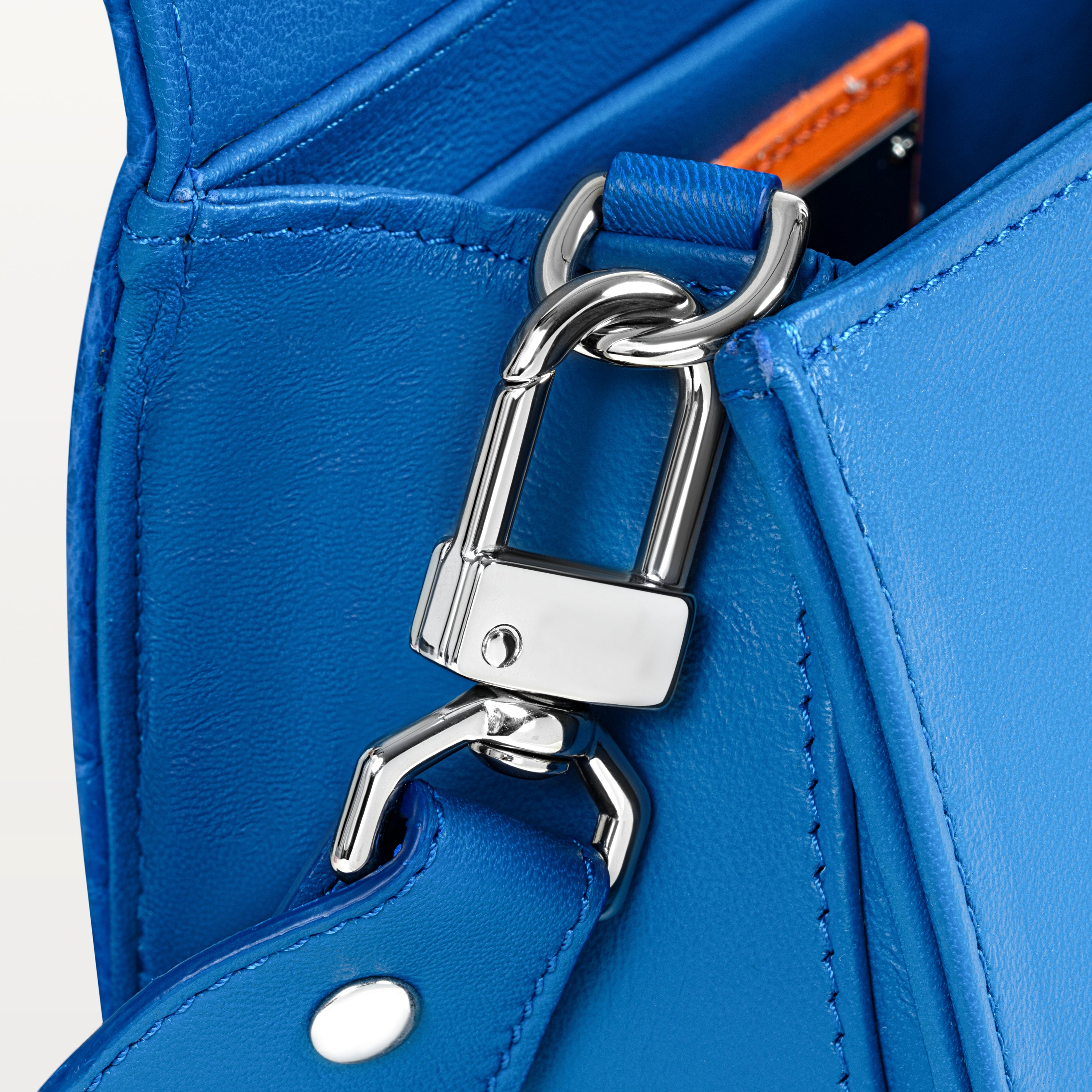 Close up view of the side gusset of the cobalt blue Lola crossbody bag in pirarucu fish leather along with the silver D-ring and crossbody strap attachment. 