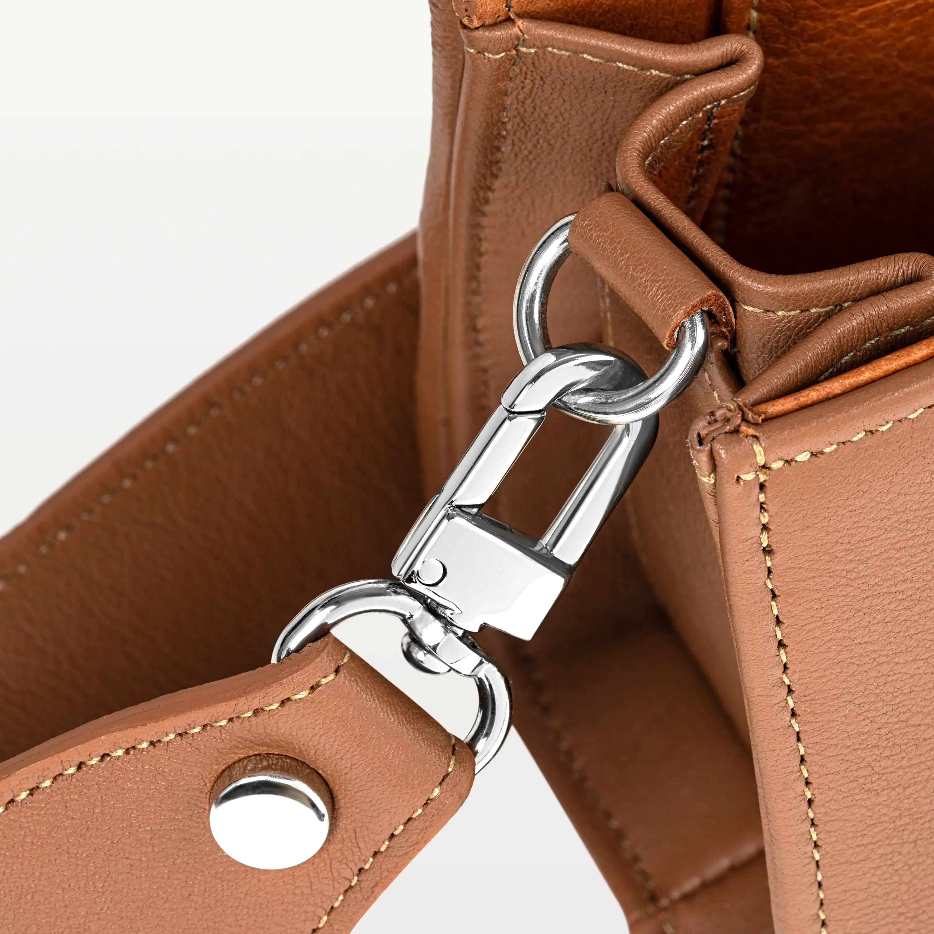 Close up view of the side gusset of the cognac Lola crossbody bag in pirarucu fish leather along with the silver D-ring and crossbody strap attachment. 
