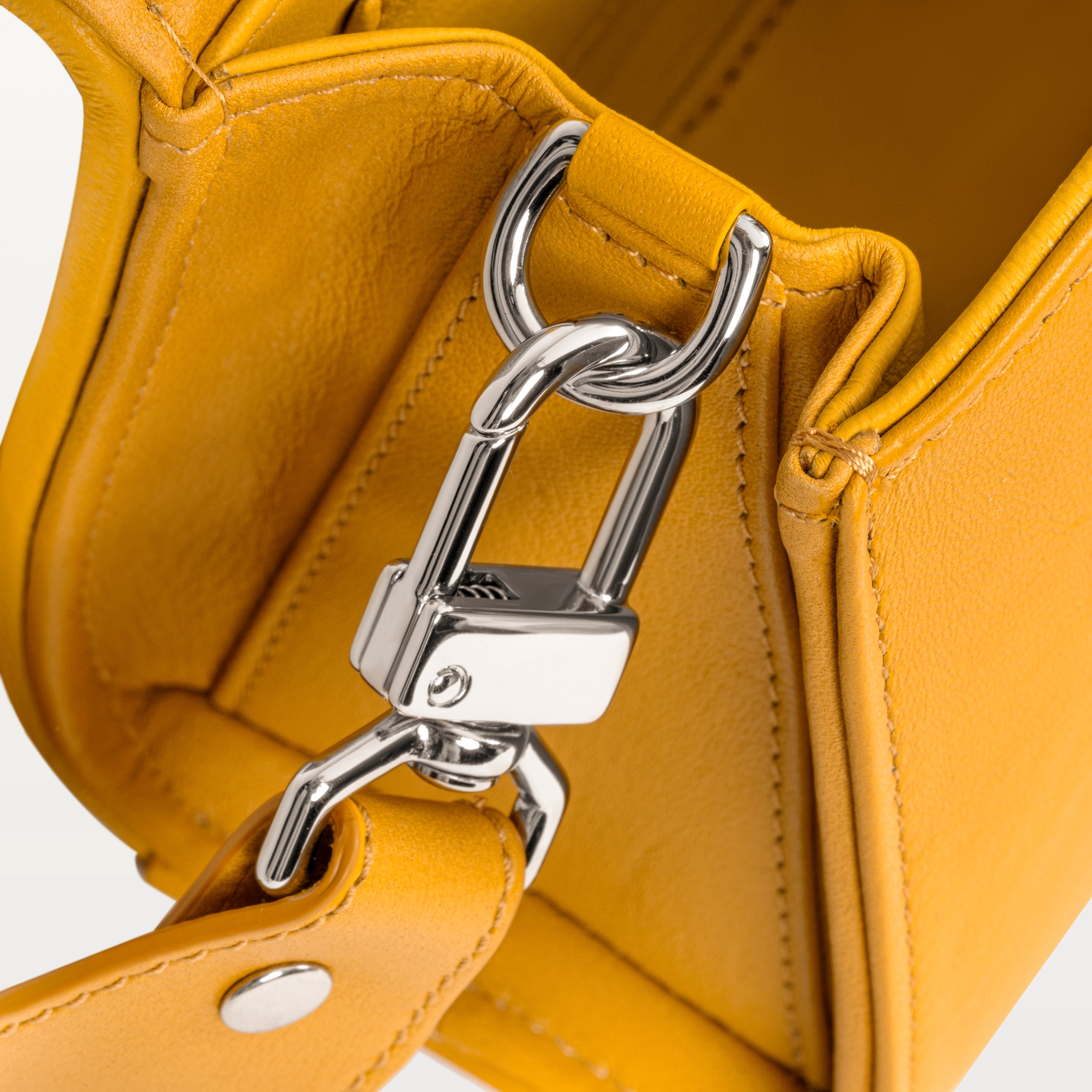 Close up view of the side gusset of the honey yellow Lola crossbody bag in pirarucu fish leather along with the silver D-ring and crossbody strap attachment. 