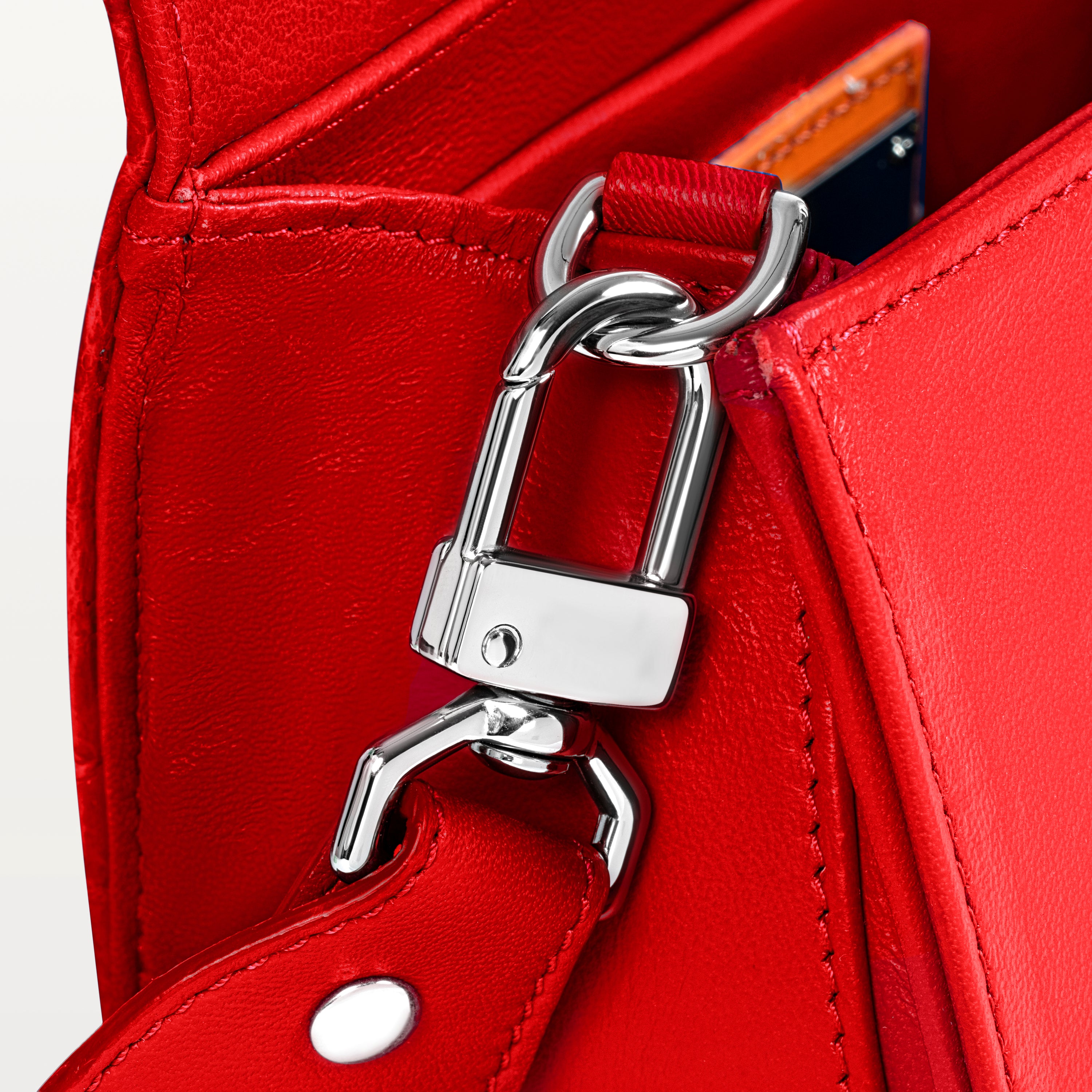 Close up view of the side gusset of the red Lola crossbody bag in pirarucu fish leather along with the silver D-ring and crossbody strap attachment. 