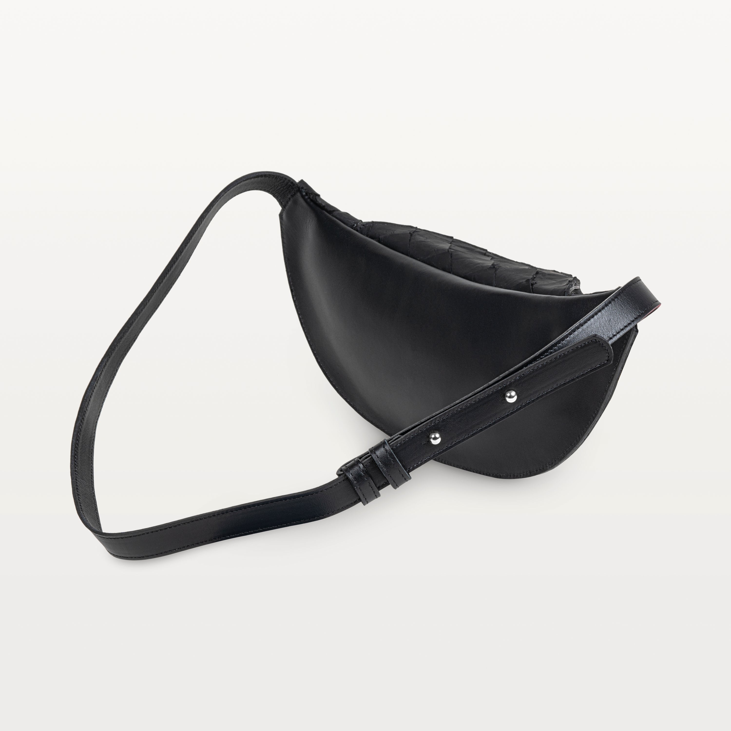 Back of the black pirarucu Mac Pack showing the bovine leather backside of the body and adjustable leather strap. 