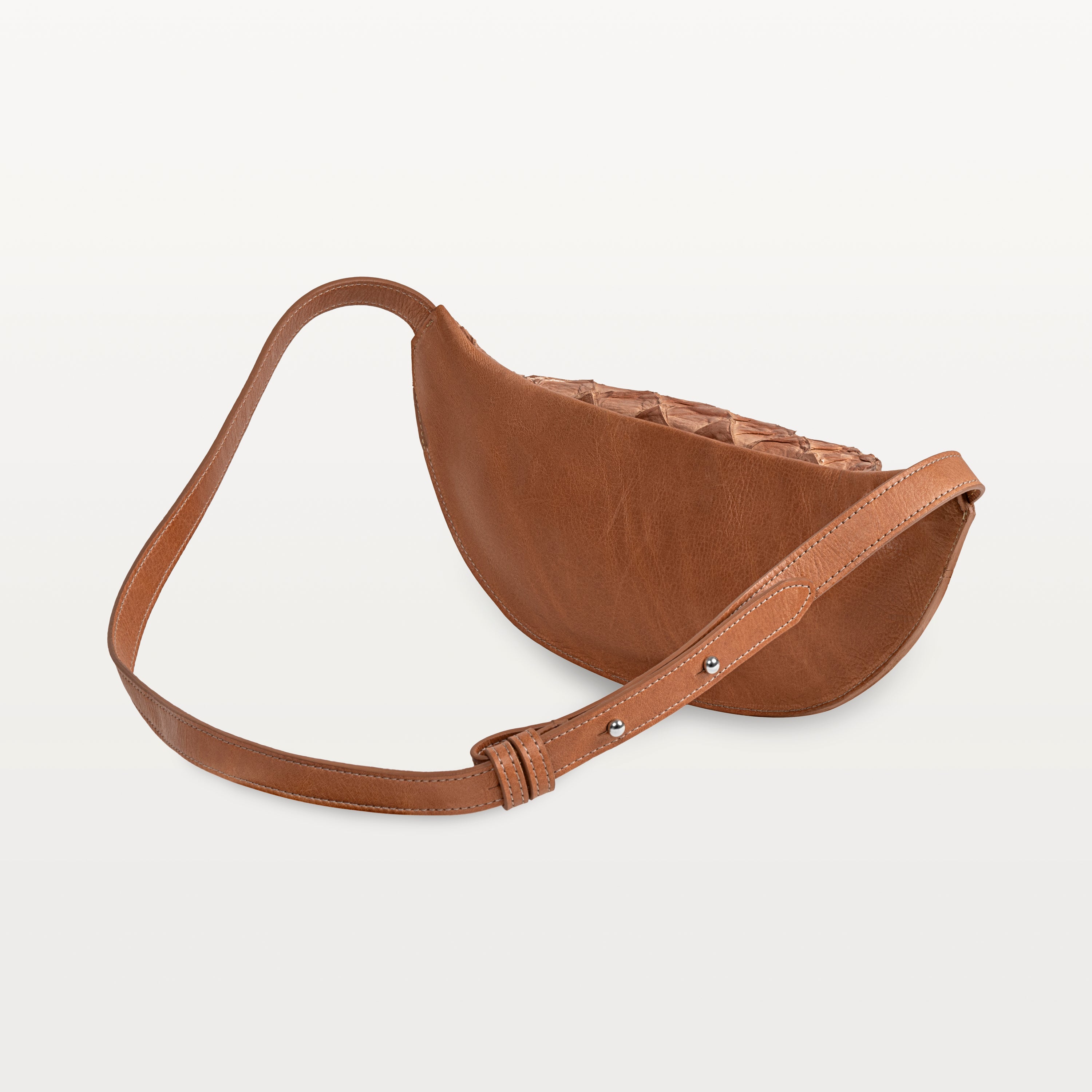 Back of the cognac pirarucu Mac Pack showing the bovine leather backside of the body and adjustable leather strap. 