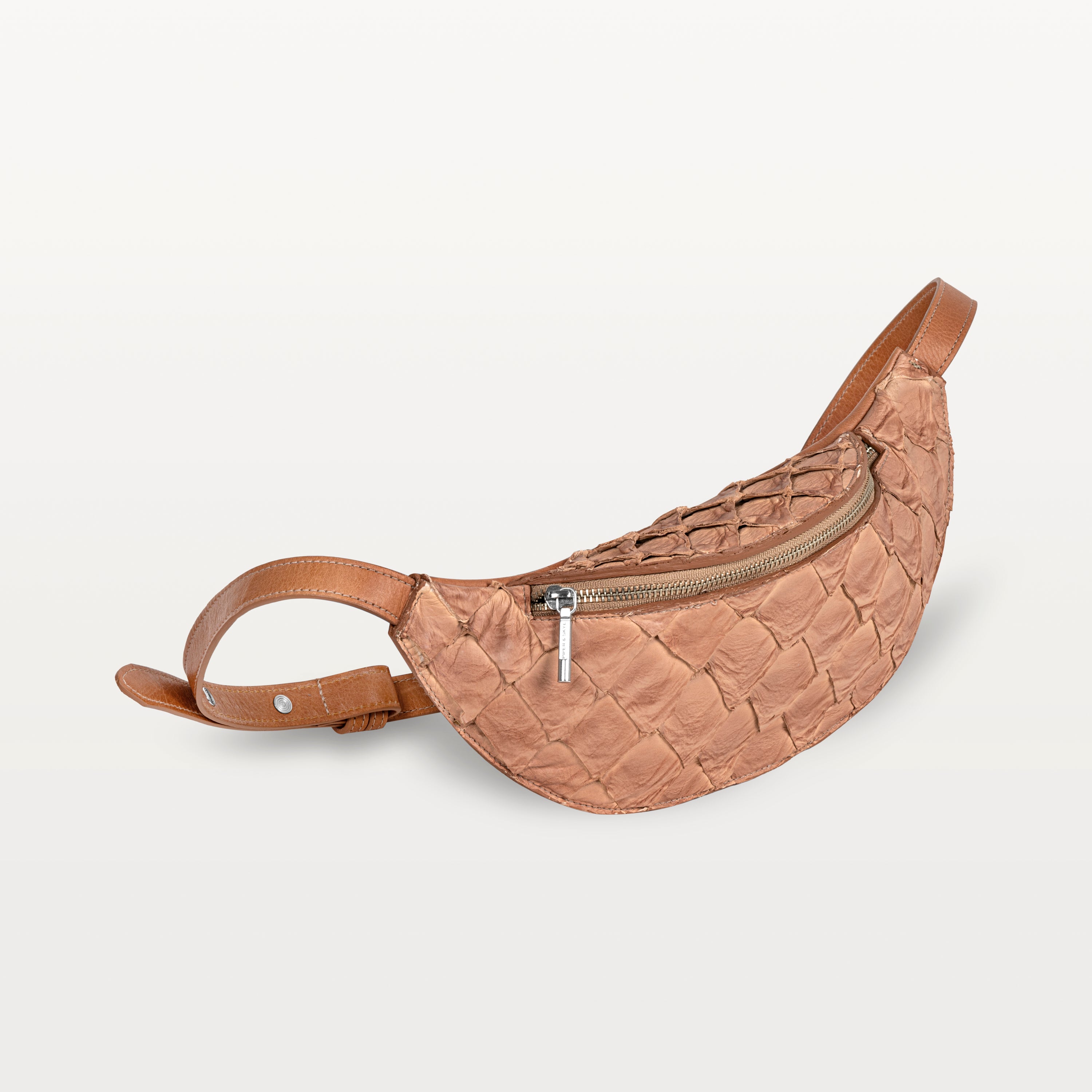 Side view of the Mac Pack belt bag in cognac pirarucu fish leather showing the tapered body and adjustable leather belt strap. 