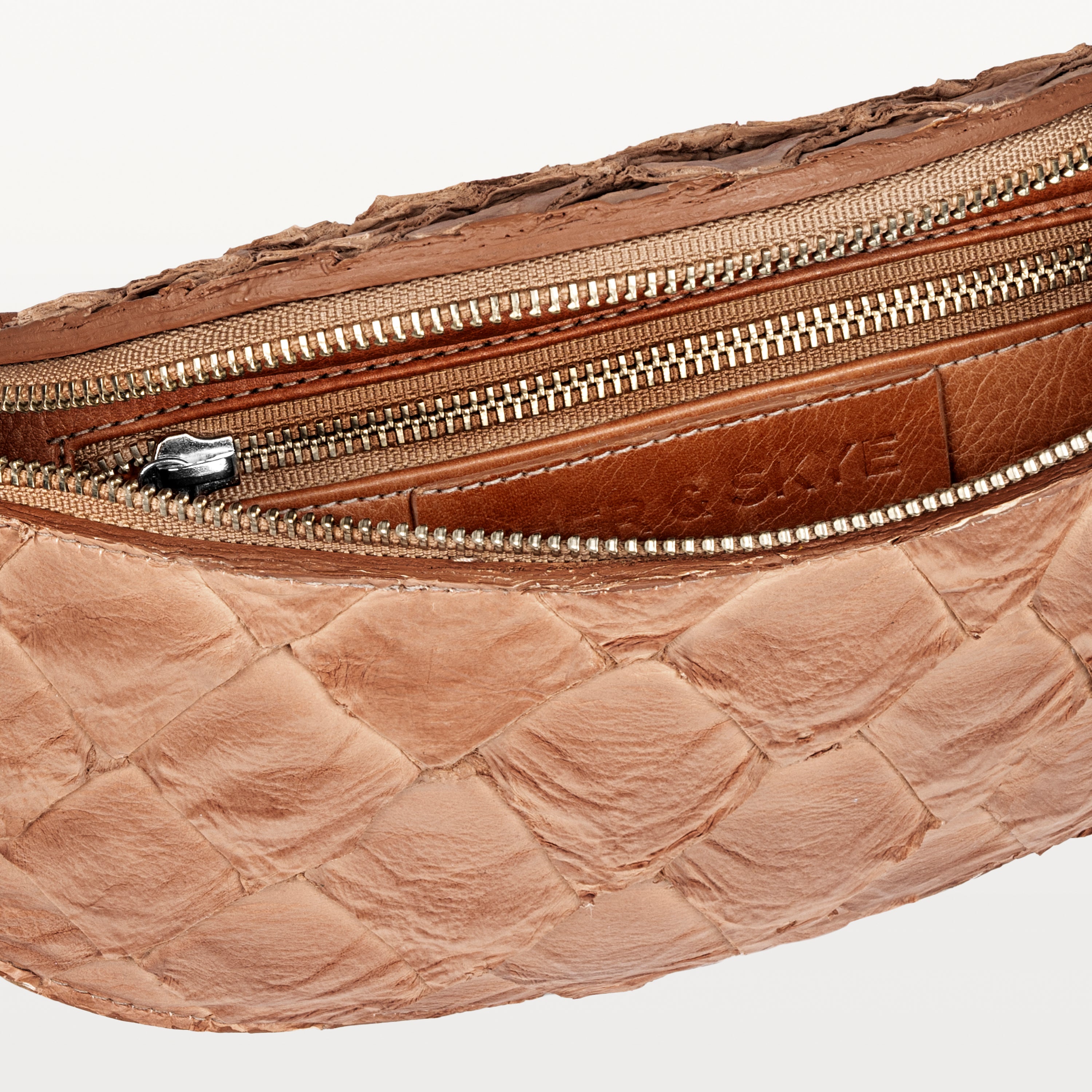 Beige interior of the cognac pirarucu Mac Pack belt bag showing the inner zippered pocket. 