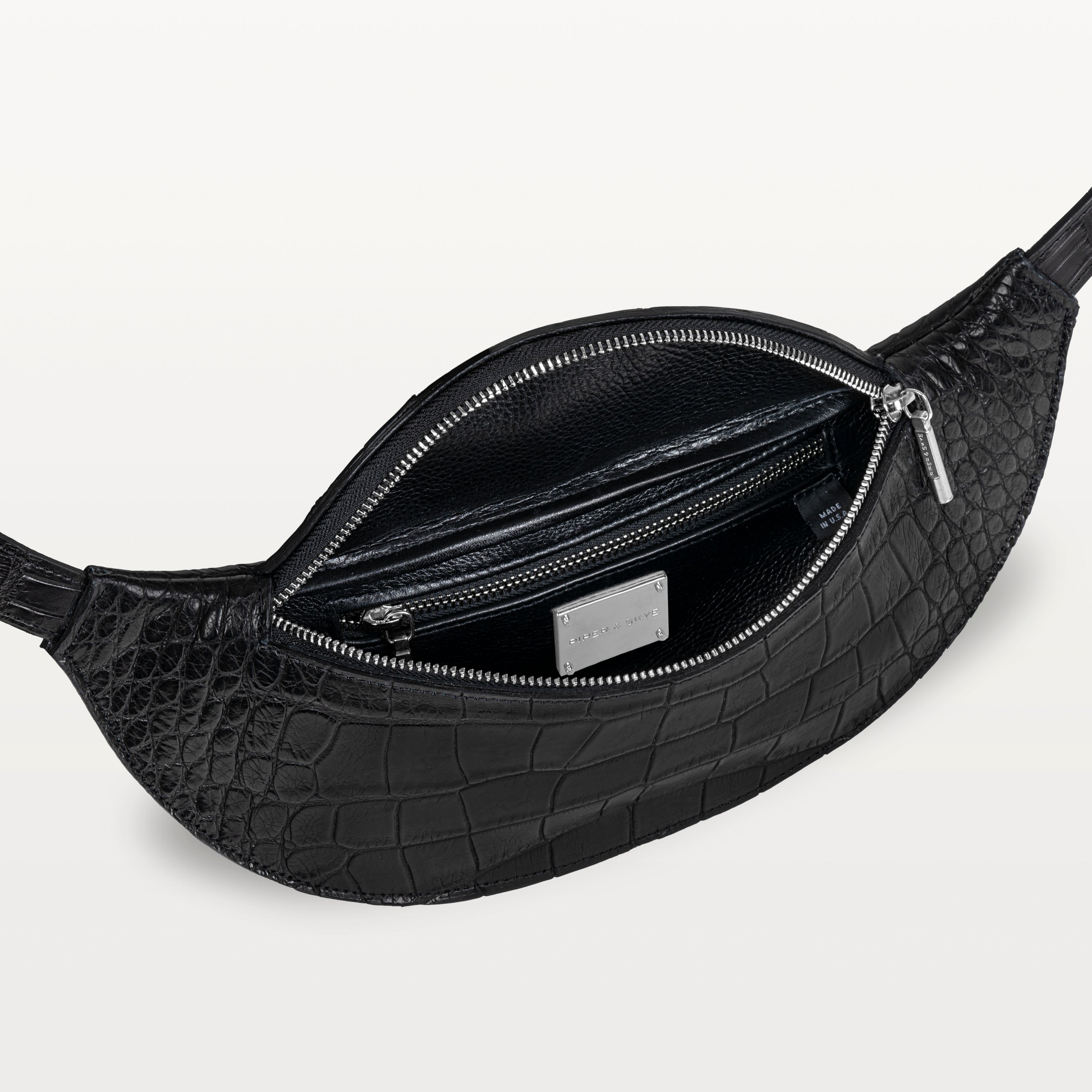 Mac Pack belt bag in black alligator leather with the top zipper open revealing an inner zippered pocket