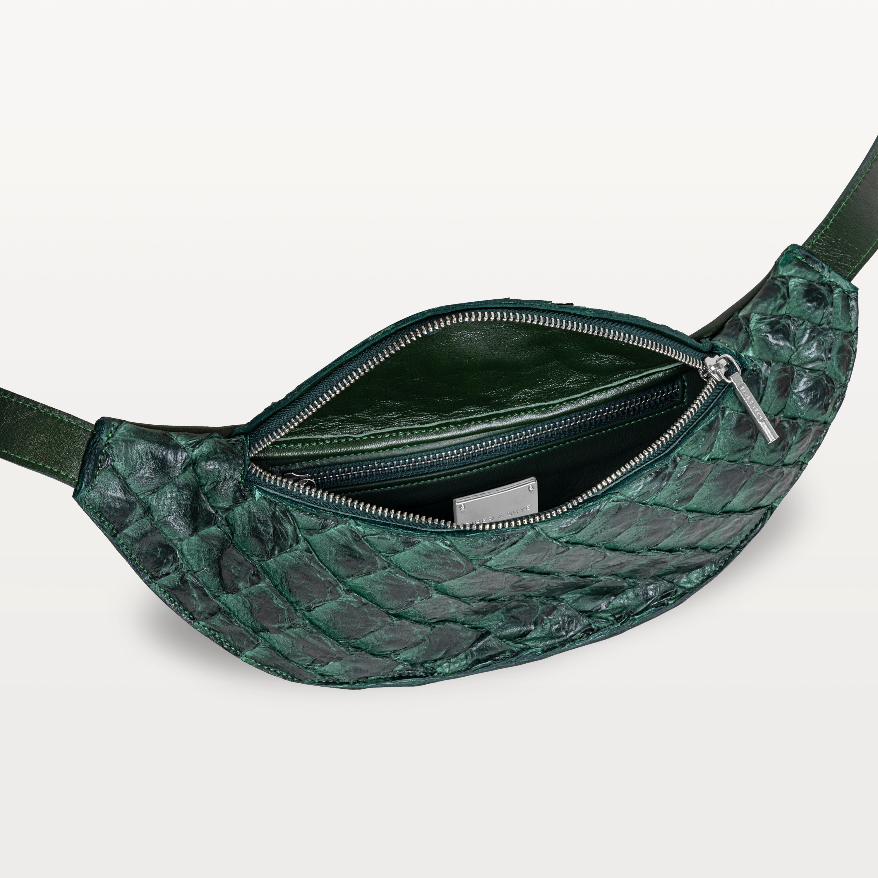 Mac Pack belt bag in verdant green pirarucu fish leather with the top zipper open revealing an inner zippered pocket