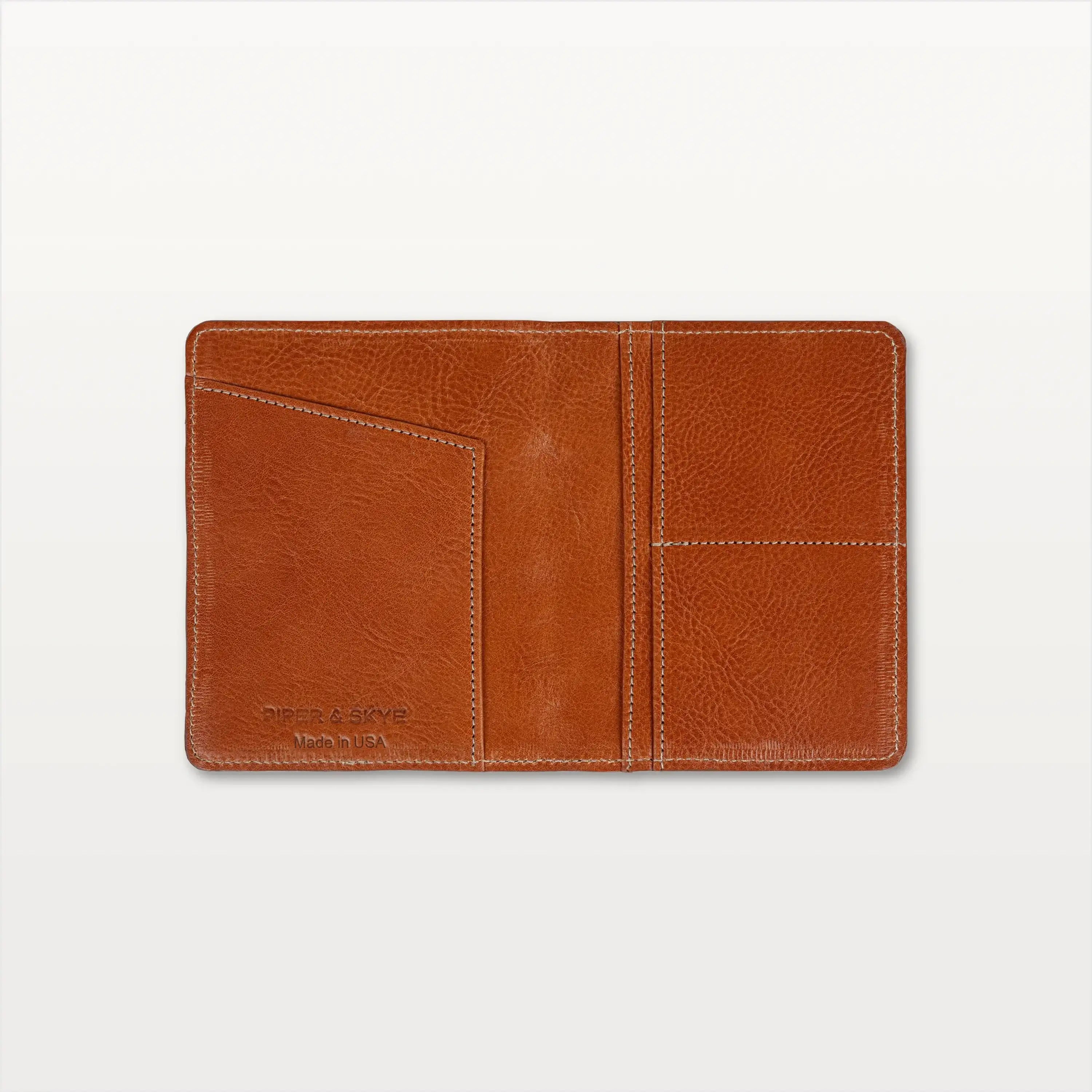 Open view of the cognac pirarucu leather passport holder showing the leather interior and slip pockets. 
