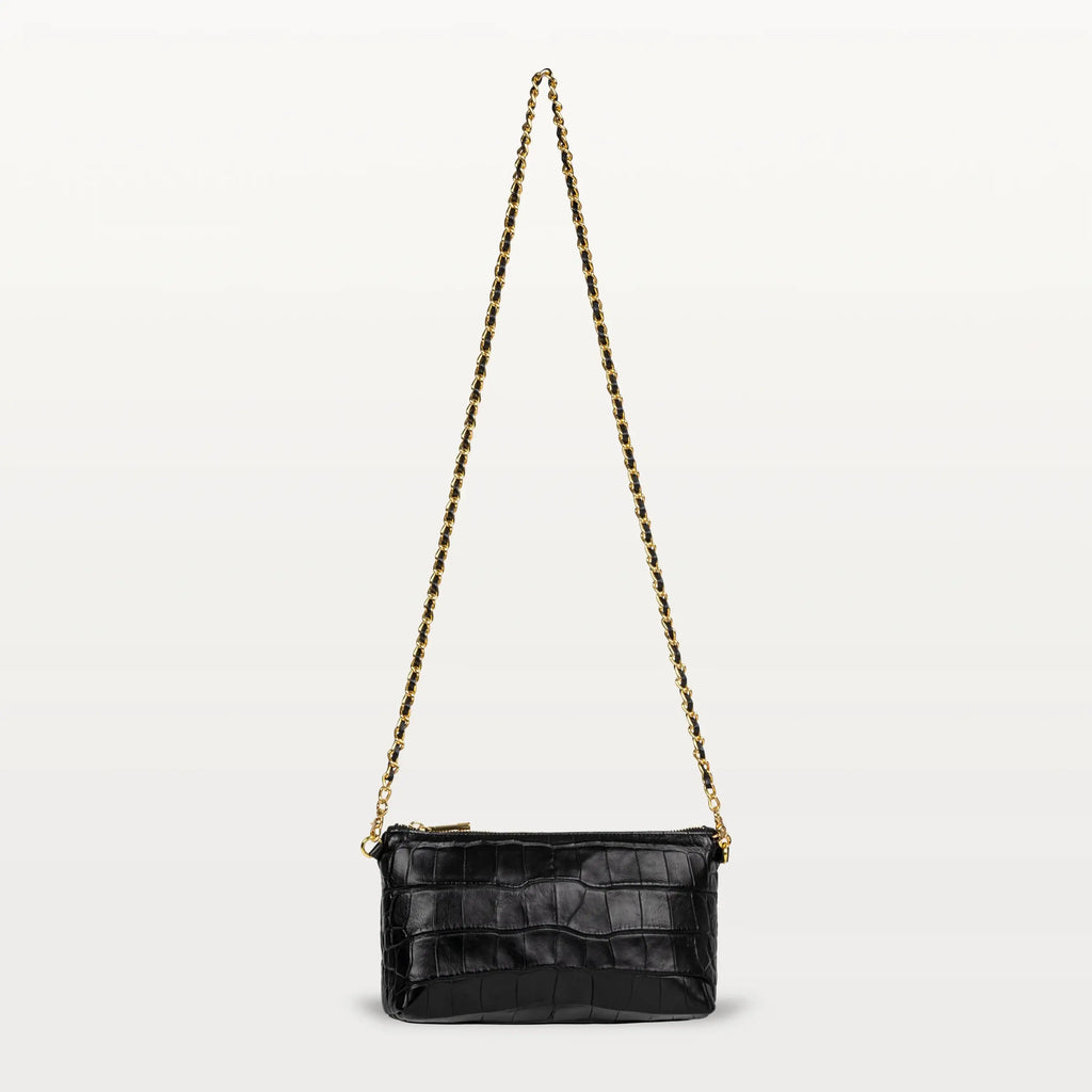 A small rectangular crossbody bag made from glossy black alligator with a long gold and black chain strap and gold zipper.