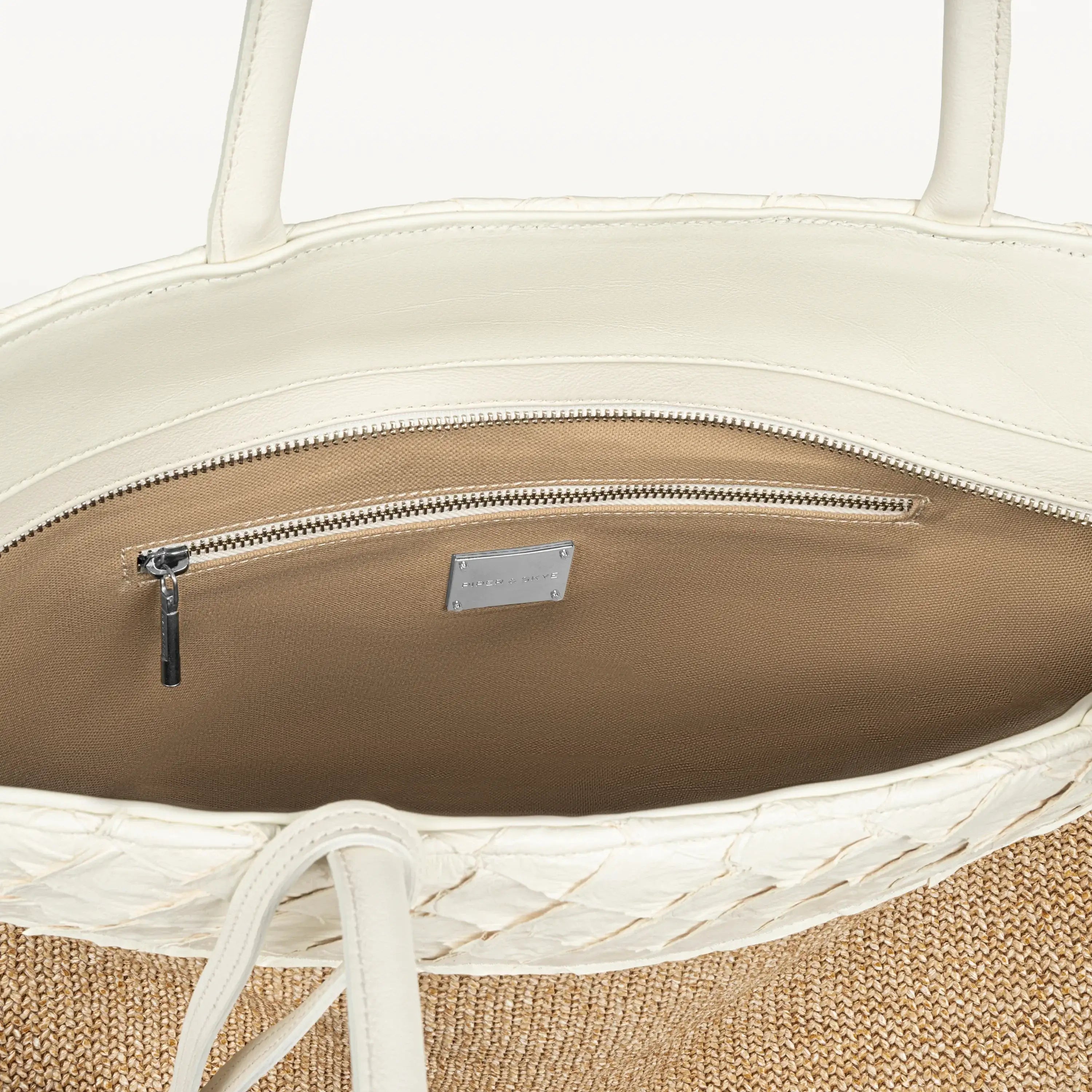 The top zipper of the Rio Beach Bag in clay white pirarucu leather is open showing the beige interior lining and inner zipper pocket. 