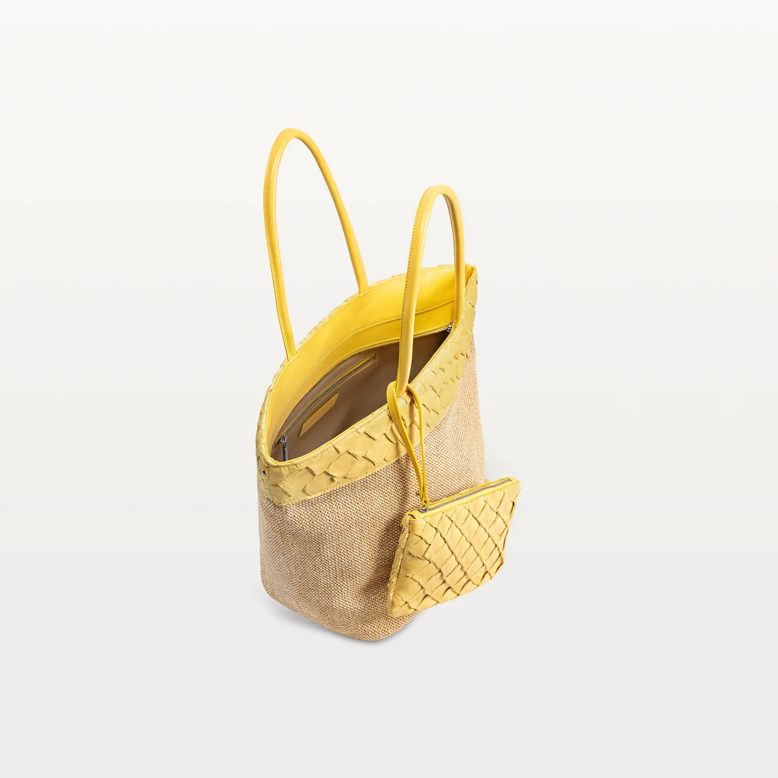 A top view of the Rio Beach Bag in honey yellow pirarucu leather with its top zipper open. A matching wristlet hangs from the strap. 