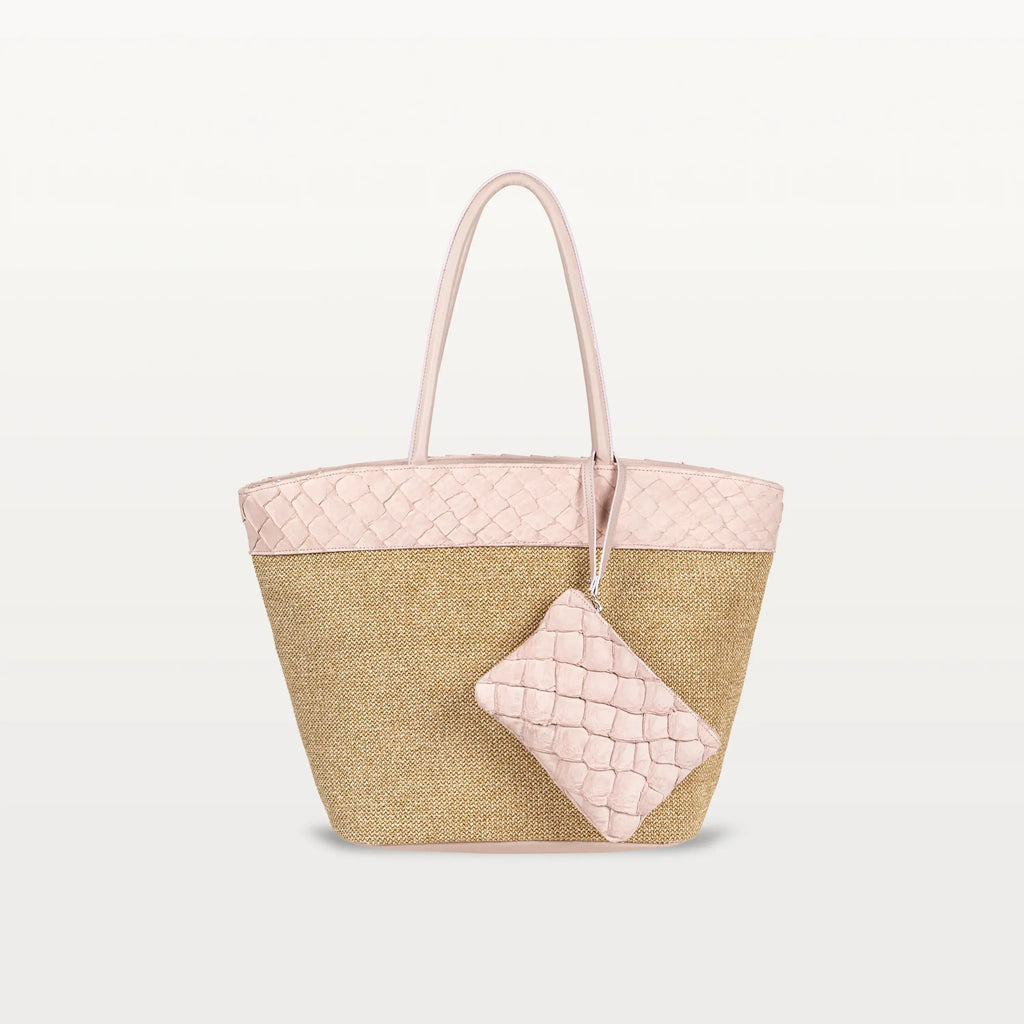 The Rio Beach Bag with a camel raffia body and pink pirarucu leather trim. A matching pink pirarucu leather wristlet hangs from the strap