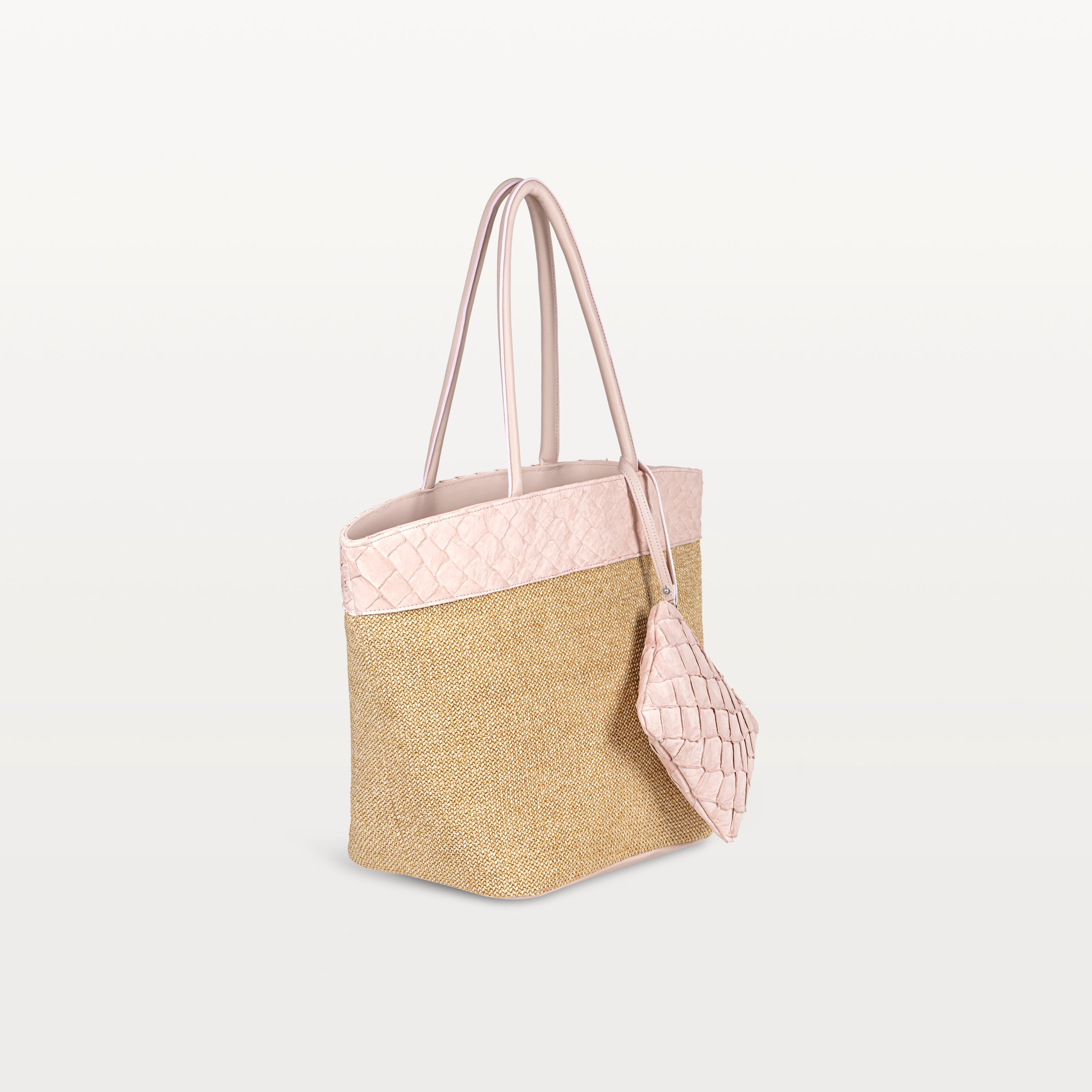 Side view of the Rio Beach Bag with a camel raffia body and pink pirarucu leather trim. A matching pink pirarucu leather wristlet hangs from the strap