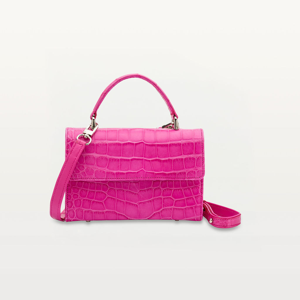 The structured Soho top handle bag in glossy azalea pink alligator leather with a top handle, crossbody strap and silver hardware.