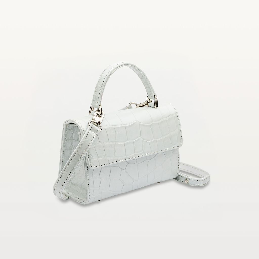 Side view of Piper & Skye's sustainable leather Soho Top Handle crossbody handbag in Moonstone White.